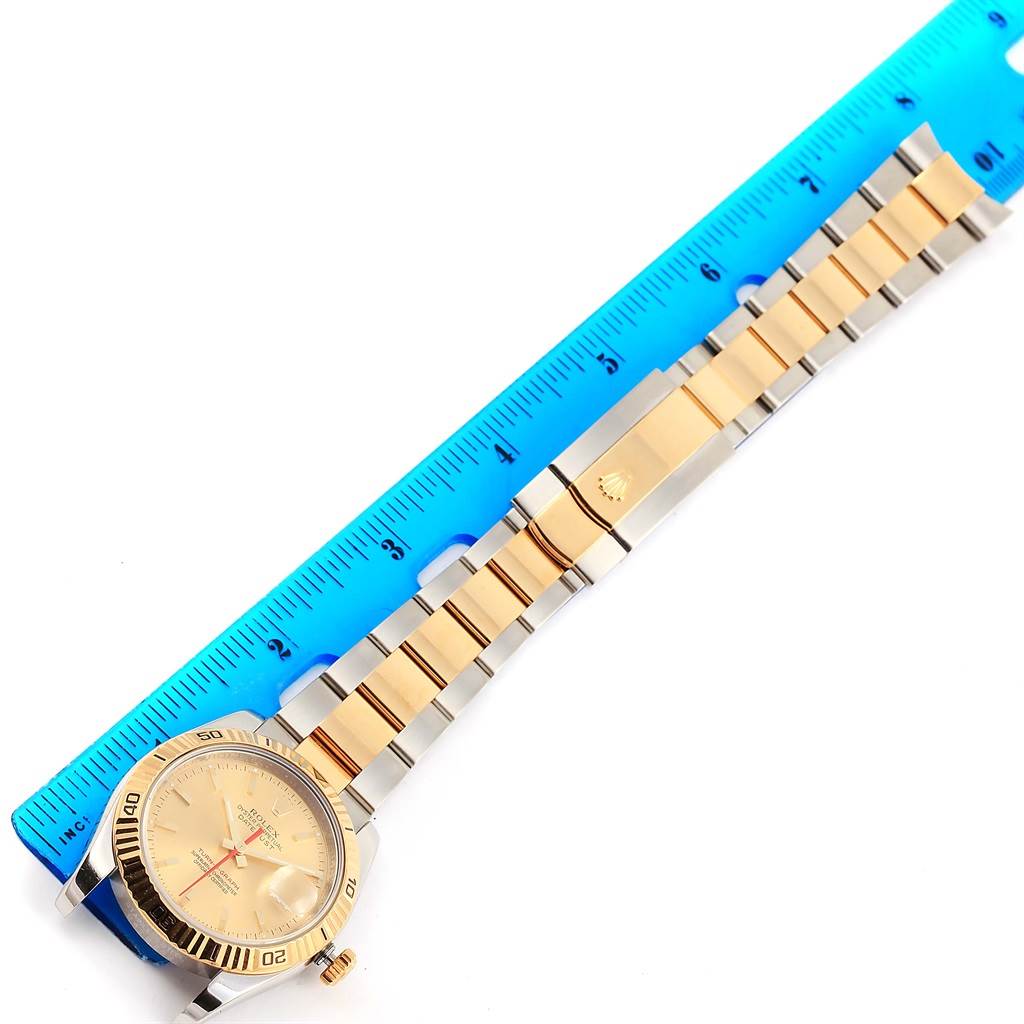 The image shows a Rolex Turn-o-Graph 116263 Men
s Stainless Steel Champagne Dial 116263 Men
s Stainless Steel Champagne Dial watch laid flat with its band extended next to a blue ruler for measurement.