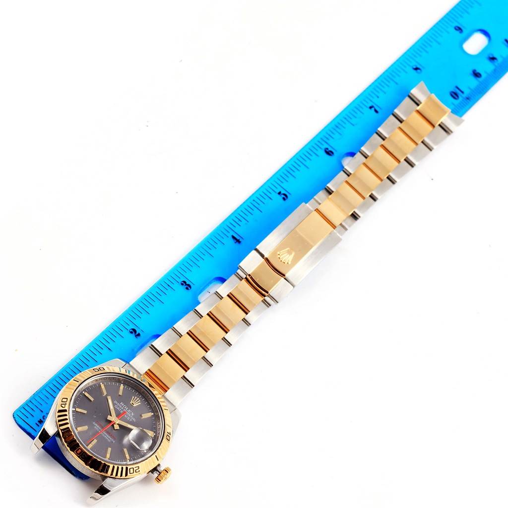 The Rolex Turn-o-Graph 116263 Men's Steel and Gold (two tone) Grey Dial 116263 Men's Steel and Gold (two tone) Grey Dial watch is shown from a top-down angle, displaying its face, bezel, and two-tone bracelet next to a ruler.