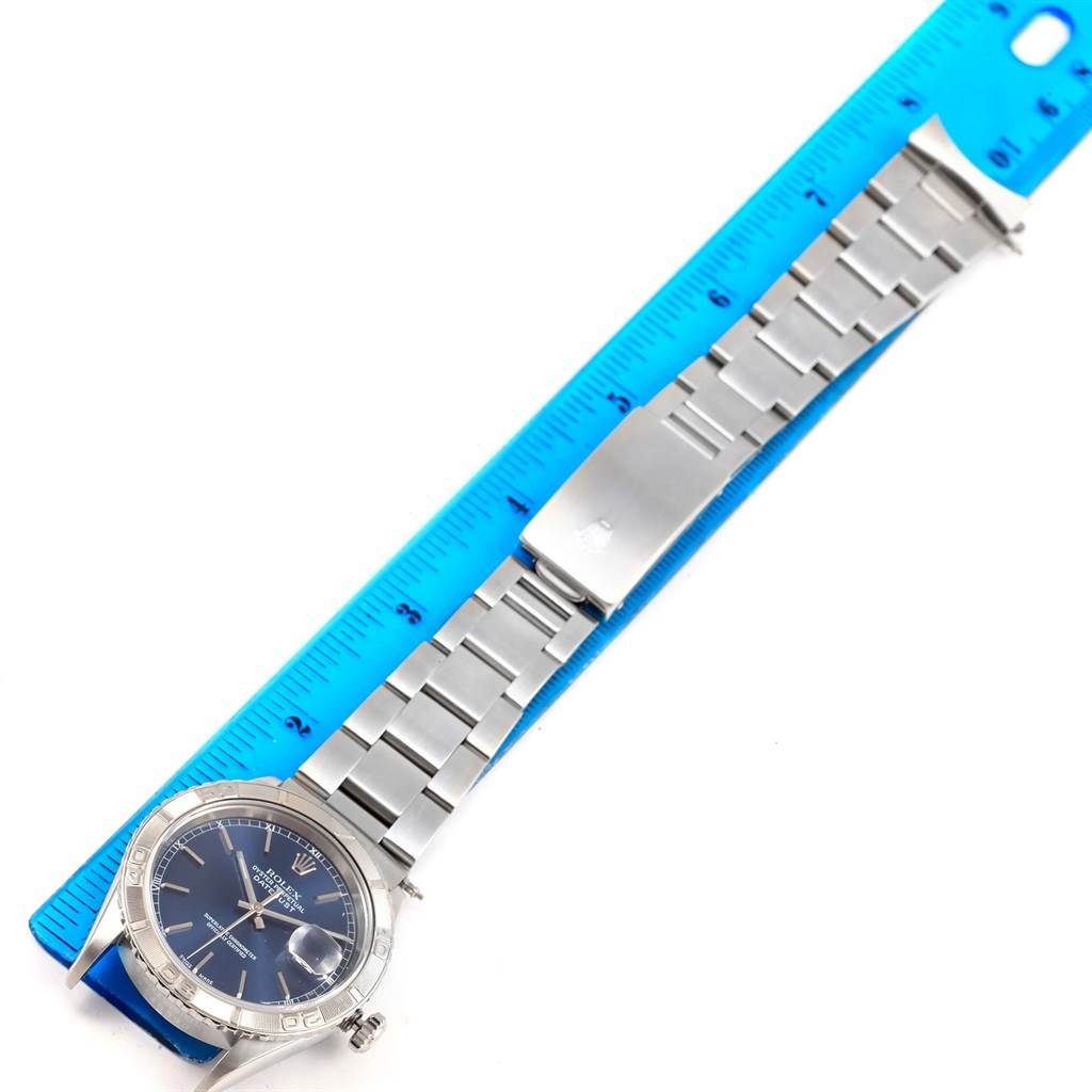 The image shows the full length of the Rolex Turn-o-Graph 16264 Men's Stainless Steel Blue Dial 16264 Men's Stainless Steel Blue Dial watch placed alongside a blue ruler.