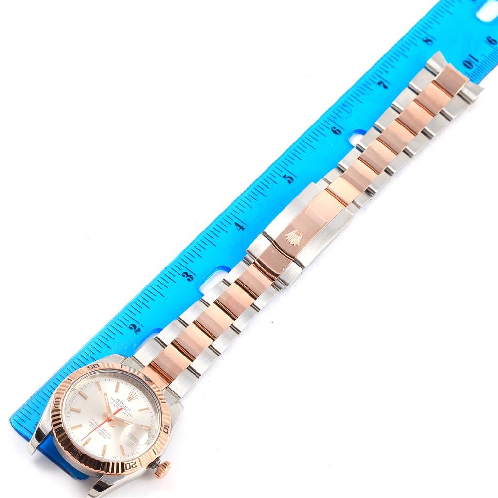 The image shows a Turn-o-Graph model by Rolex, viewed from above, displaying its face, bezel, and bracelet alongside a ruler.