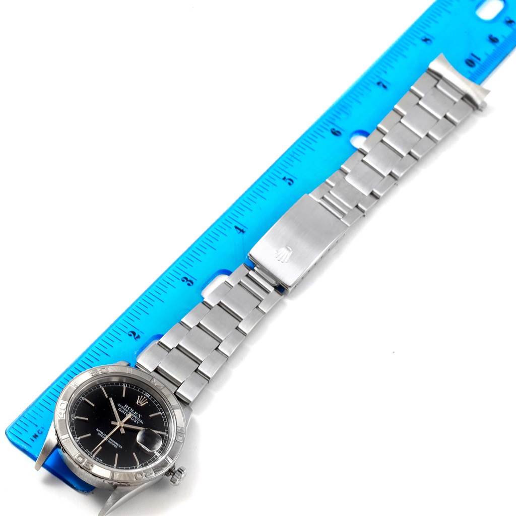 The image shows a Rolex Turn-o-Graph 16264 Men
s Stainless Steel Black Dial 16264 Men
s Stainless Steel Black Dial watch resting beside a ruler, with the face, bezel, and full bracelet visible.