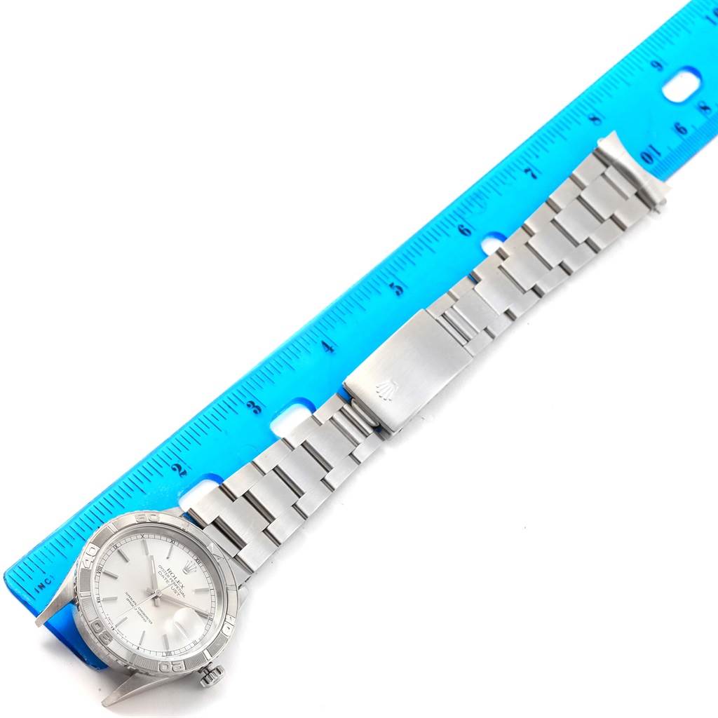 The image shows the Rolex Turn-o-Graph 16264 Men's Stainless Steel Silver Dial 16264 Men's Stainless Steel Silver Dial watch laid flat alongside a blue ruler for size comparison.