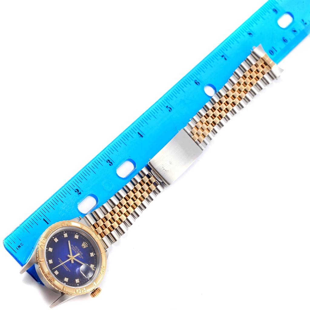The image shows a Rolex Turn-o-Graph 16263 Men
s Steel and Gold (two tone) Blue Dial 16263 Men
s Steel and Gold (two tone) Blue Dial watch laid flat, with a blue ruler measuring its length.