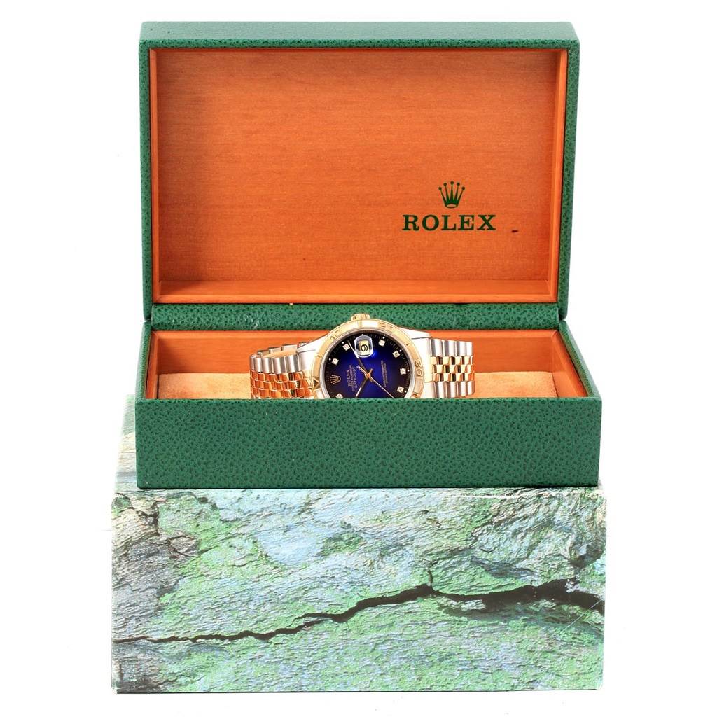 The Rolex Turn-o-Graph 16263 Men
s Steel and Gold (two tone) Blue Dial 16263 Men
s Steel and Gold (two tone) Blue Dial model is displayed in its open green and orange box, showing the watch face and bracelet.
