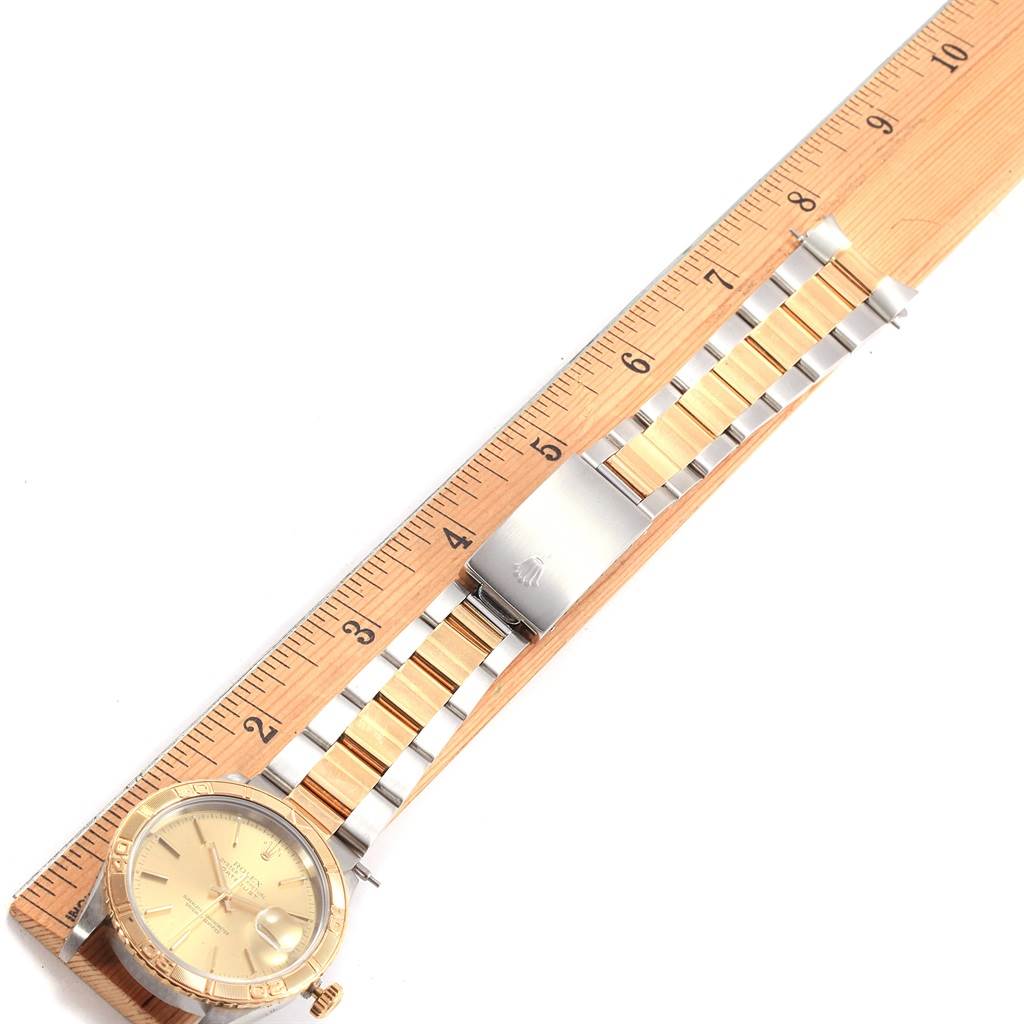 The Rolex Turn-o-Graph 16263 Men
s Steel and Gold (two tone) Champagne Dial 16263 Men
s Steel and Gold (two tone) Champagne Dial watch is positioned diagonally, showing the dial and entire bracelet beside a wooden ruler.