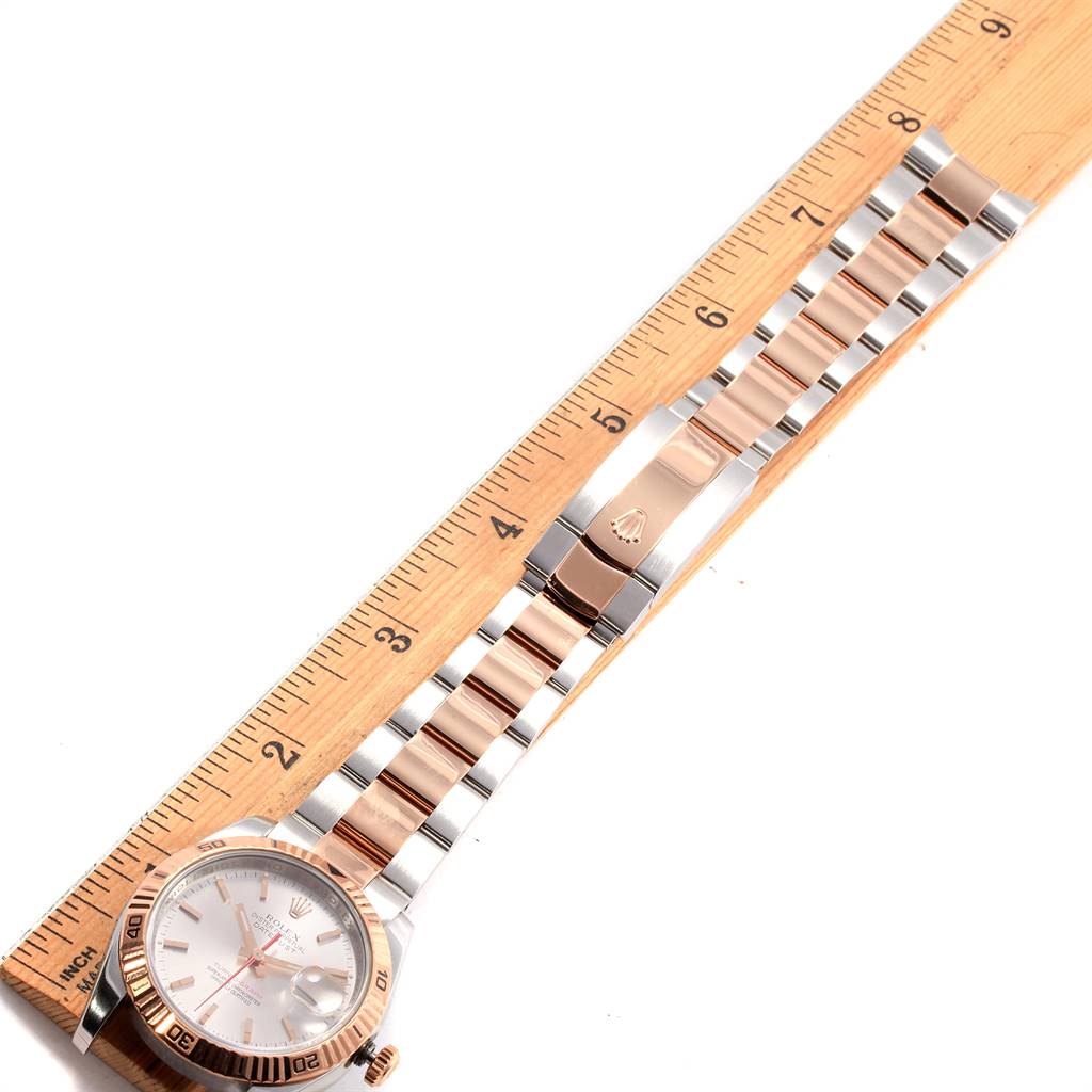 The Rolex Turn-o-Graph 116261 Men
s Stainless Steel Silver Dial 116261 Men
s Stainless Steel Silver Dial watch is shown from an overhead angle, displaying the face, bezel, and entire bracelet length beside a ruler.