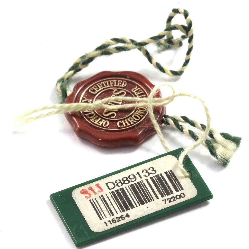 The image shows a green tag with a barcode and a red wax seal, both accessories for the Rolex Turn-o-Graph 116264 Men
s Stainless Steel Black Dial 116264 Men
s Stainless Steel Black Dial model.