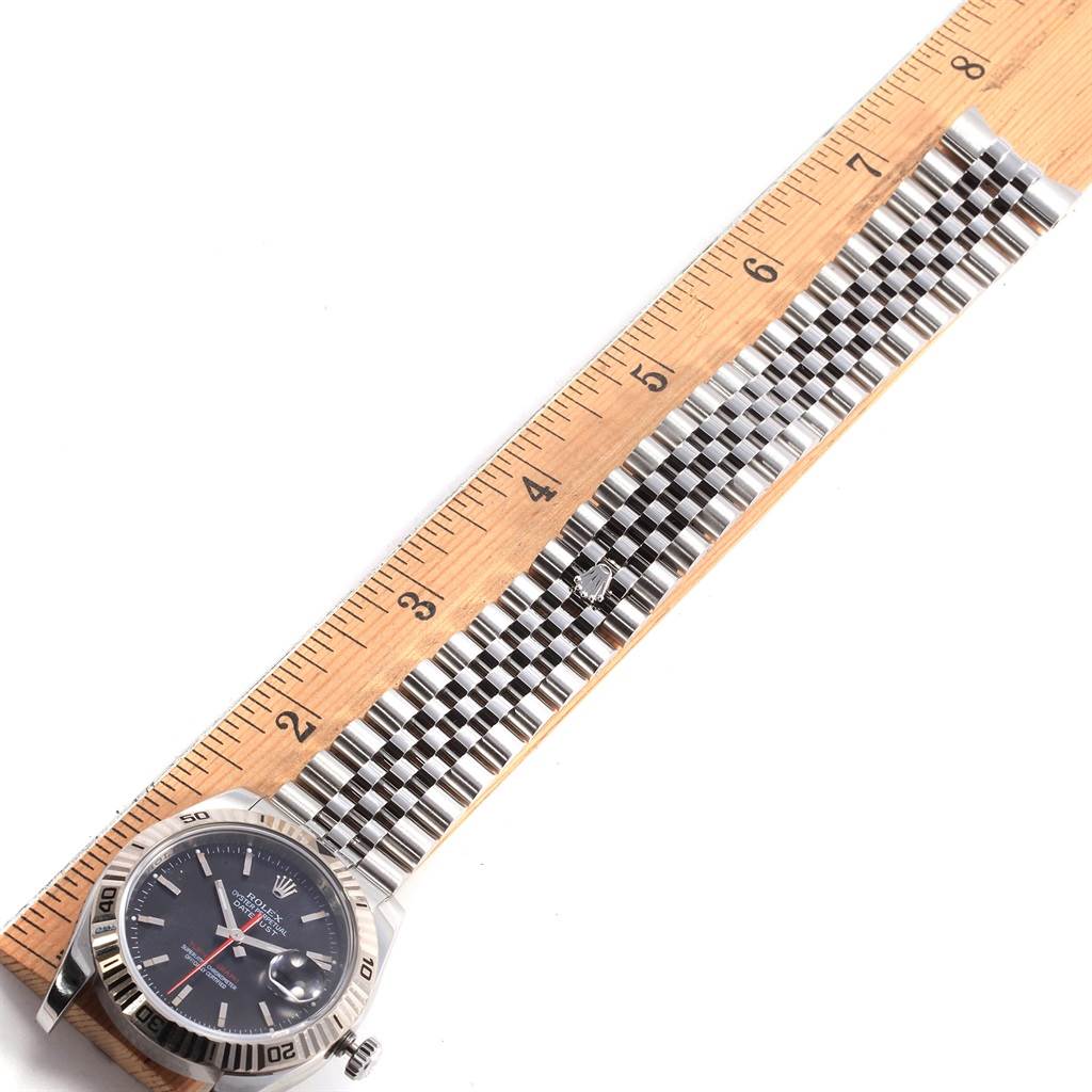 The Rolex Turn-o-Graph 116264 Men
s Stainless Steel Black Dial 116264 Men
s Stainless Steel Black Dial watch is shown at an angle displaying its face, bezel, and full metal strap against a ruler for scale.