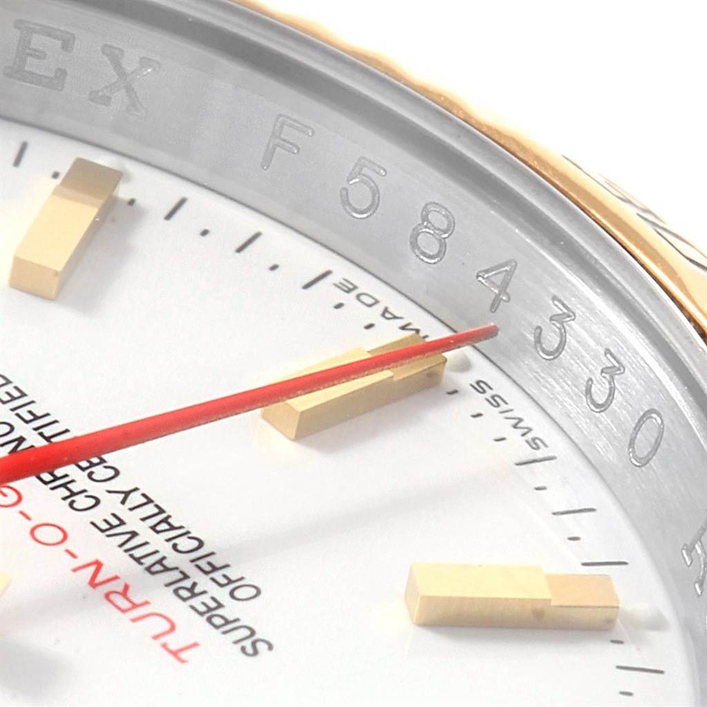 This close-up angle of the Rolex Turn-o-Graph 116263 Men's Stainless Steel White Dial 116263 Men's Stainless Steel White Dial watch shows part of the dial, gold markers, and a red seconds hand.