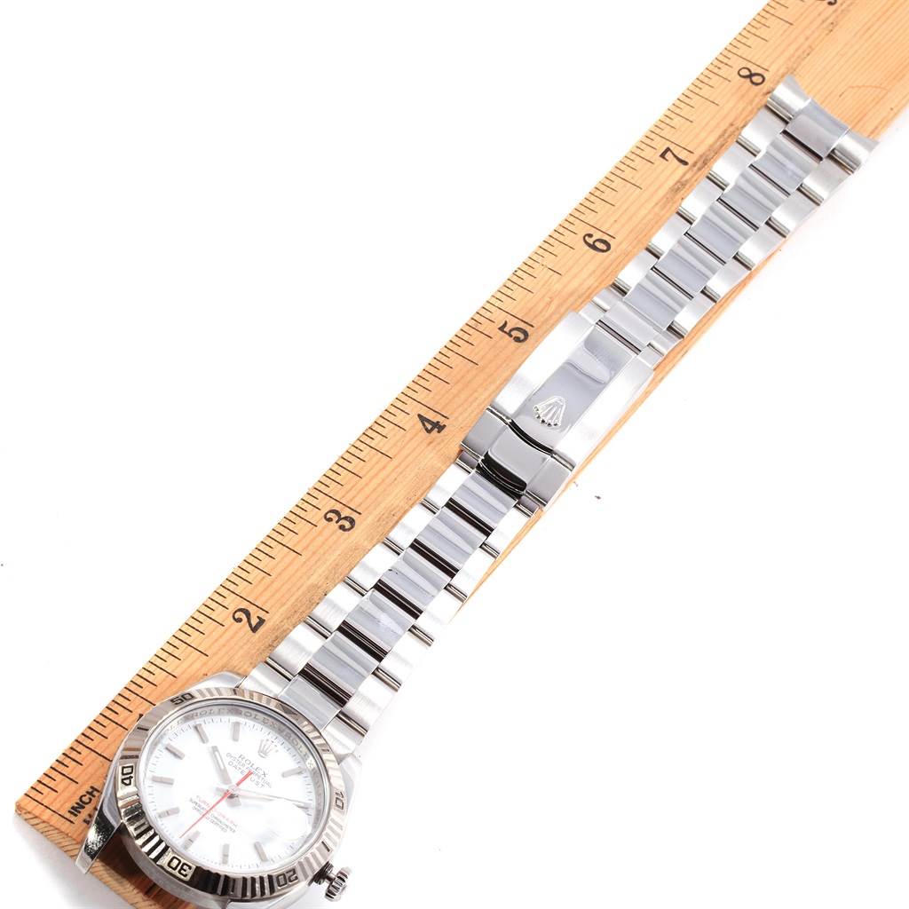 A Rolex Turn-o-Graph 116264 Men's Stainless Steel White Dial 116264 Men's Stainless Steel White Dial watch is shown from above, highlighting its face, bezel, and bracelet next to a wooden ruler for scale.