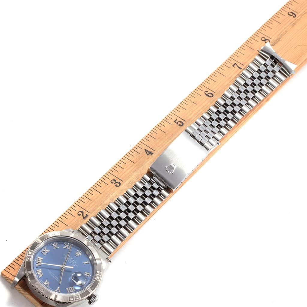 The image shows a Rolex Turn-o-Graph 16264 Men
s Stainless Steel Blue Dial 16264 Men
s Stainless Steel Blue Dial watch laid flat, with a focus on its bracelet and clasp, placed next to a ruler.