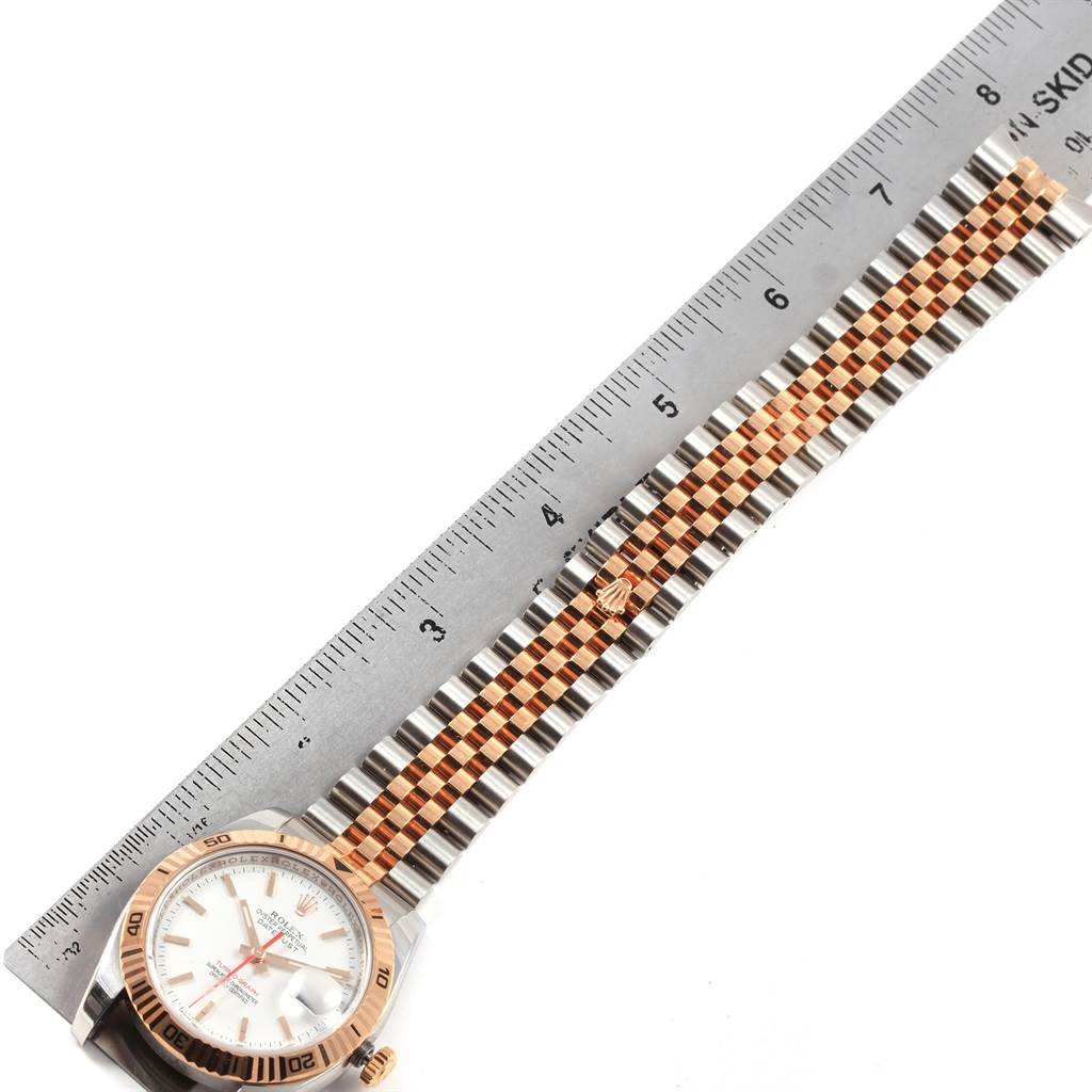 The image shows a Rolex Turn-o-Graph 116261 Men
s Stainless Steel White Dial 116261 Men
s Stainless Steel White Dial watch laid flat next to a ruler, showcasing its face, bezel, and bracelet.