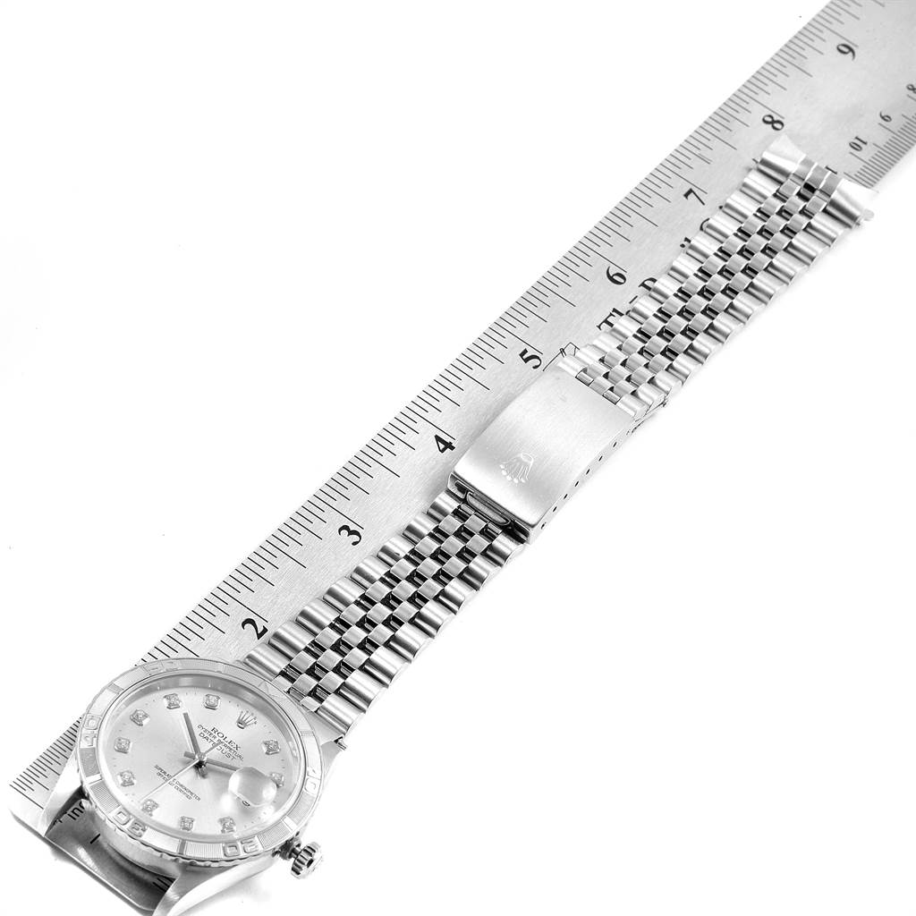 This image shows the Rolex Turn-o-Graph 16264 Men
s Stainless Steel Silver Dial 16264 Men
s Stainless Steel Silver Dial watch laid flat with its bracelet and clasp extended along a ruler.