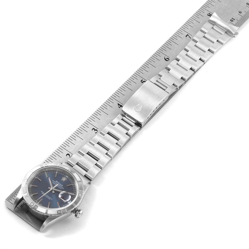 The image shows a top-down view of the Rolex Turn-o-Graph 16264 Men
s Stainless Steel Blue Dial 16264 Men
s Stainless Steel Blue Dial watch, focusing on the face, bezel, and metal bracelet laid over a ruler.