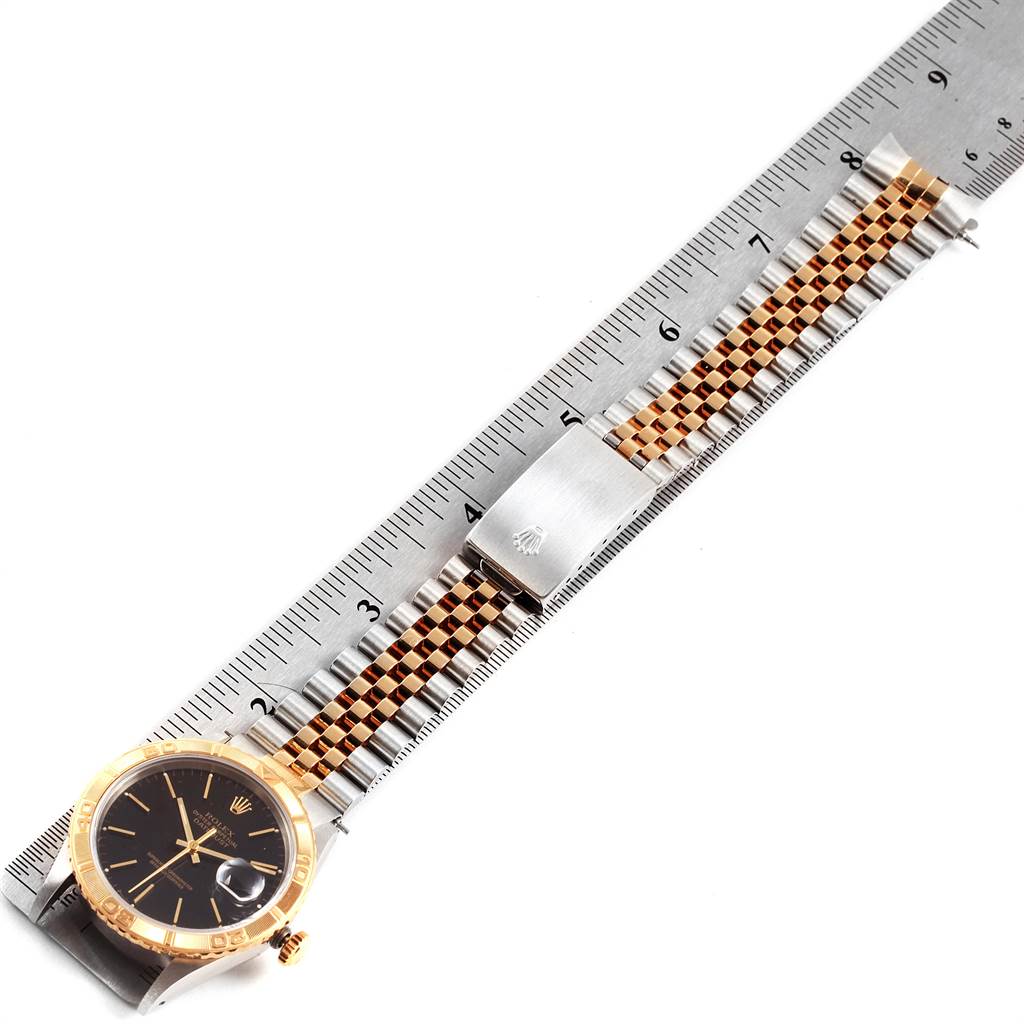 The image shows a Rolex Turn-o-Graph 16263 Men
s Steel and Gold (two tone) Black Dial 16263 Men
s Steel and Gold (two tone) Black Dial watch laying face-up alongside a ruler, with the entire band and face visible.