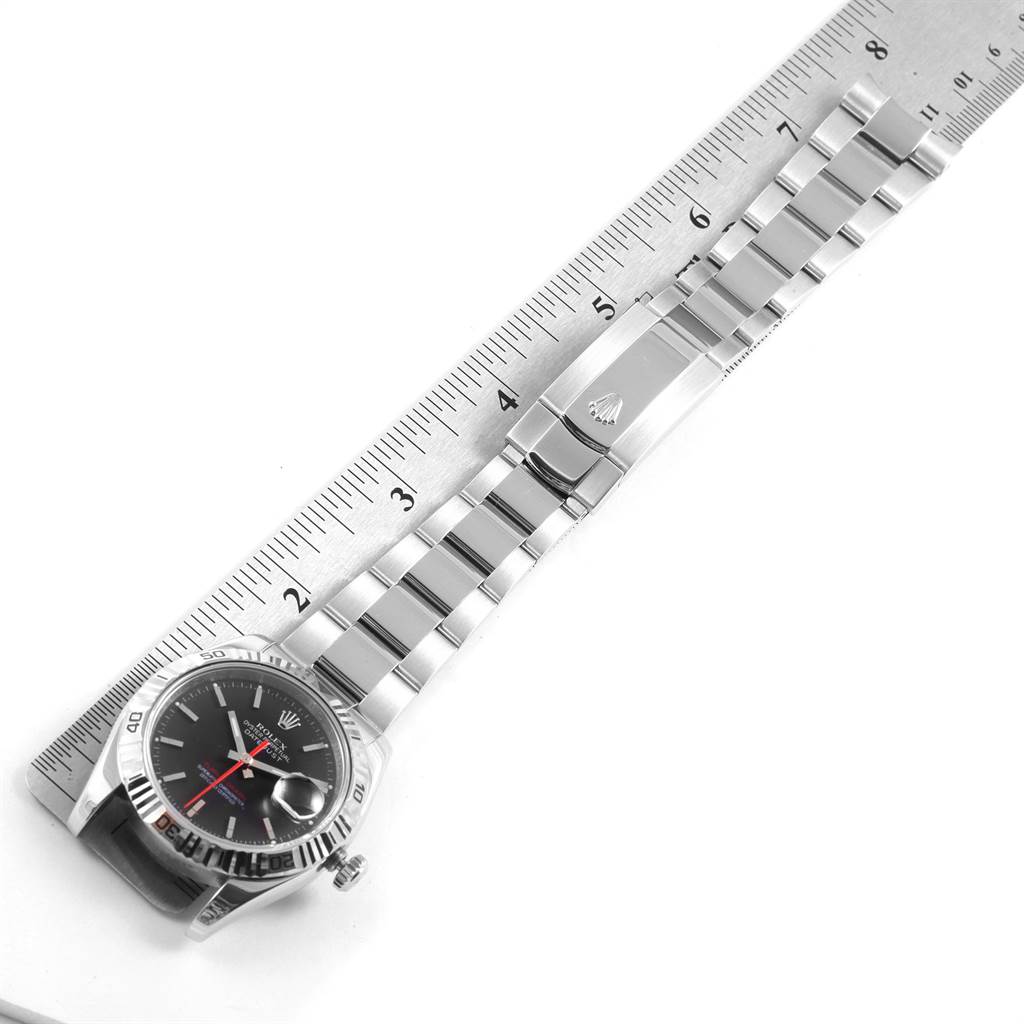 The Rolex Turn-o-Graph 116264 Men
s Stainless Steel Black Dial 116264 Men
s Stainless Steel Black Dial watch is shown from an overhead angle, displaying the face, bracelet, and clasp on a ruler.