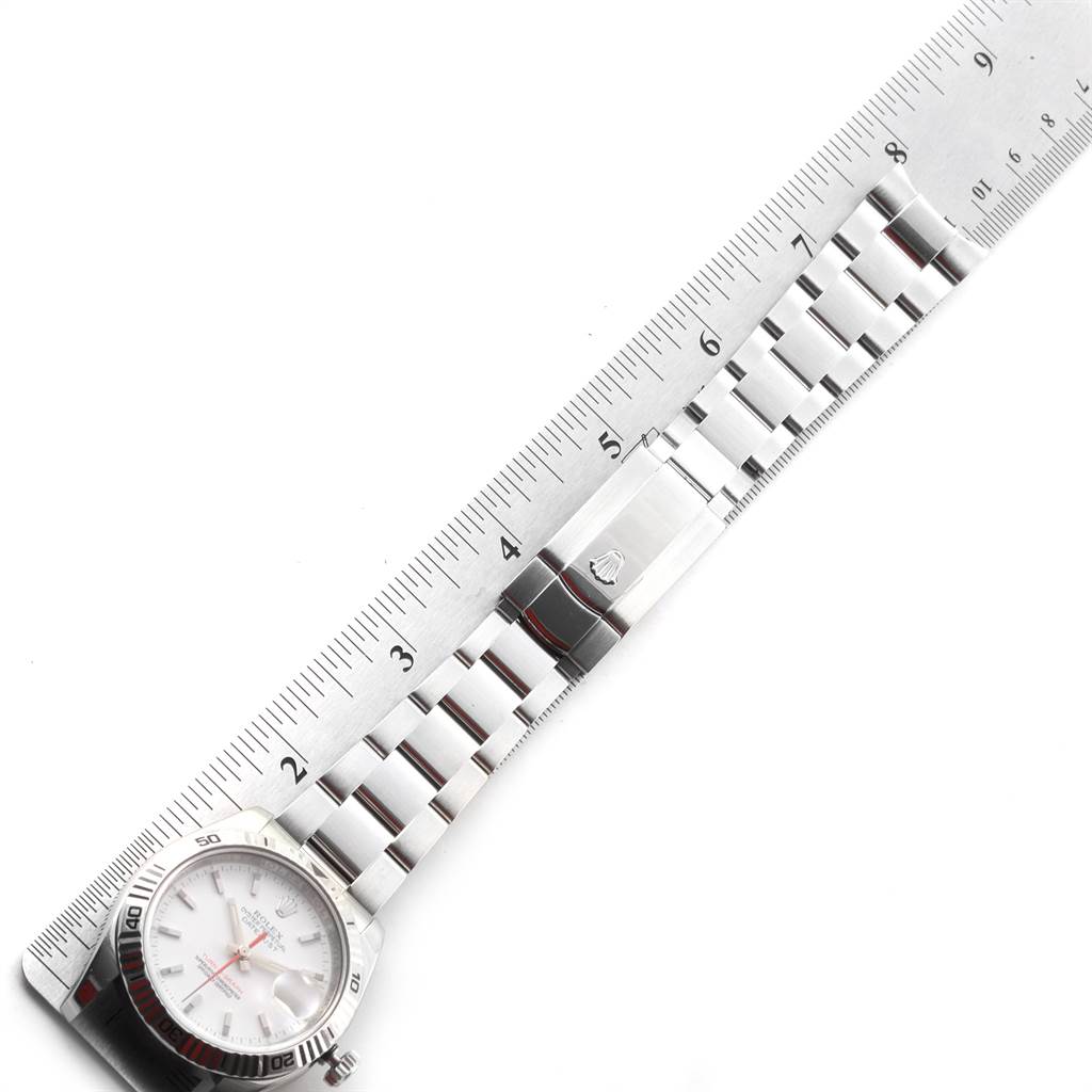 The image shows a Rolex Turn-o-Graph 116264 Men
s Stainless Steel White Dial 116264 Men
s Stainless Steel White Dial watch laid flat next to a ruler, showcasing its bracelet and clasp.