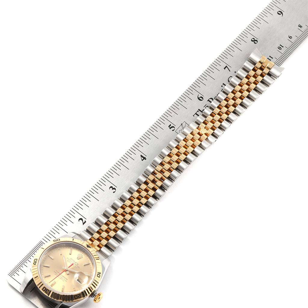 The image shows a Rolex Turn-o-Graph 116263 Men
s Stainless Steel Champagne Dial 116263 Men
s Stainless Steel Champagne Dial watch placed against a ruler, displaying its face and two-tone metal bracelet from an overhead angle.