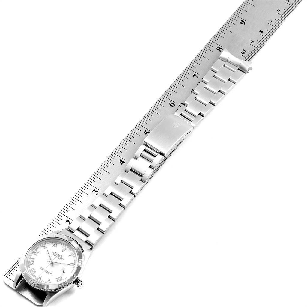 The image shows a Rolex Turn-o-Graph 16264 Men
s Stainless Steel White Dial 16264 Men
s Stainless Steel White Dial watch laid flat alongside a ruler, highlighting its face and metal band.