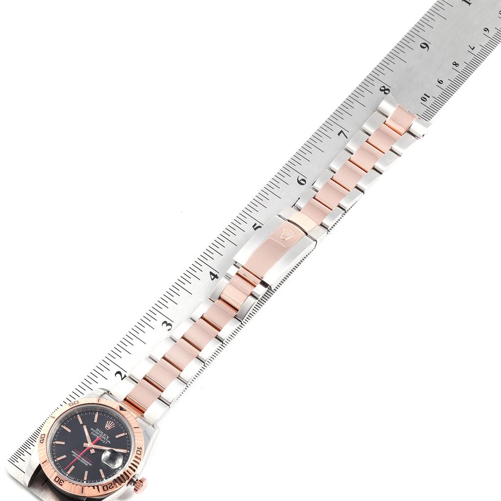 The image shows a top-down view of a Rolex Turn-o-Graph 116261 Men's Steel and Gold (two tone) Black Dial 116261 Men's Steel and Gold (two tone) Black Dial watch, highlighting its face, bezel, and bracelet against a ruler.