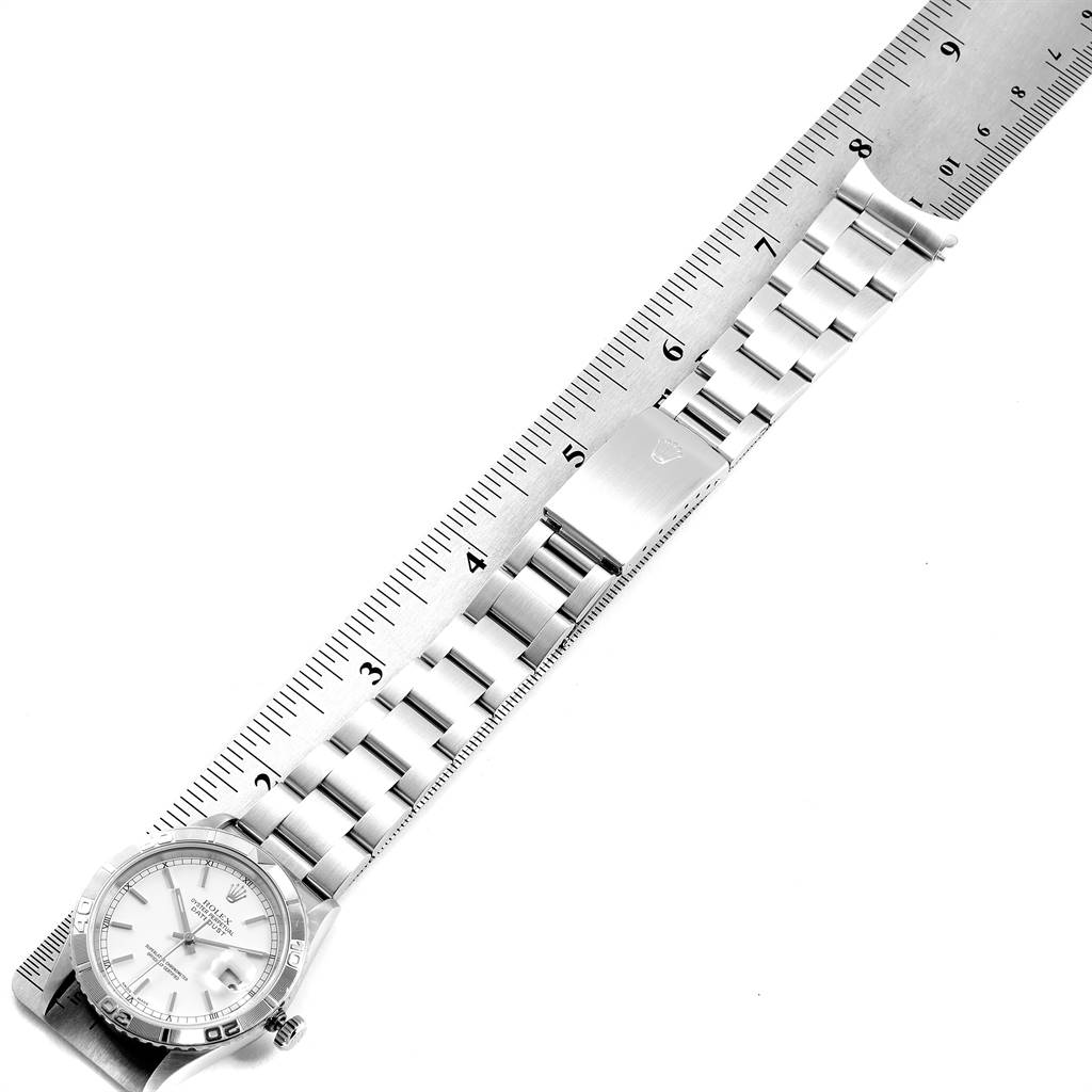 This image shows the Rolex Turn-o-Graph 16264 Men
s Stainless Steel White Dial 16264 Men
s Stainless Steel White Dial watch laid flat with a ruler, displaying its face, bracelet, and clasp.