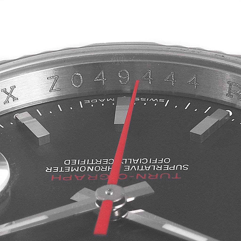 This close-up image of a Rolex Turn-o-Graph 116264 Men's Stainless Steel Black Dial 116264 Men's Stainless Steel Black Dial watch shows the red second hand, part of the black dial, markers, and engraved serial number.