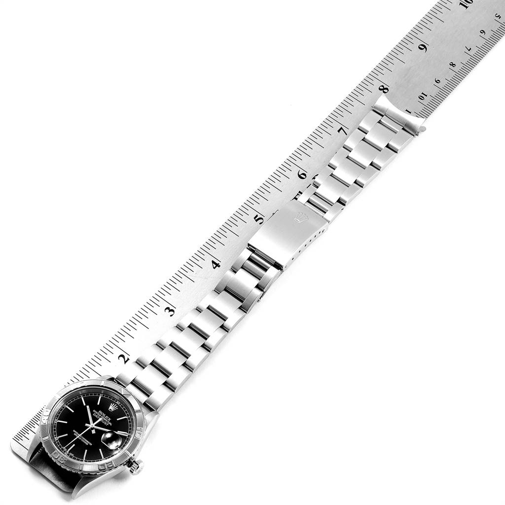The image shows a Rolex Turn-o-Graph 16264 Men
s Stainless Steel Black Dial 16264 Men
s Stainless Steel Black Dial watch placed along a ruler, showcasing the band and dial from a top-down angle.