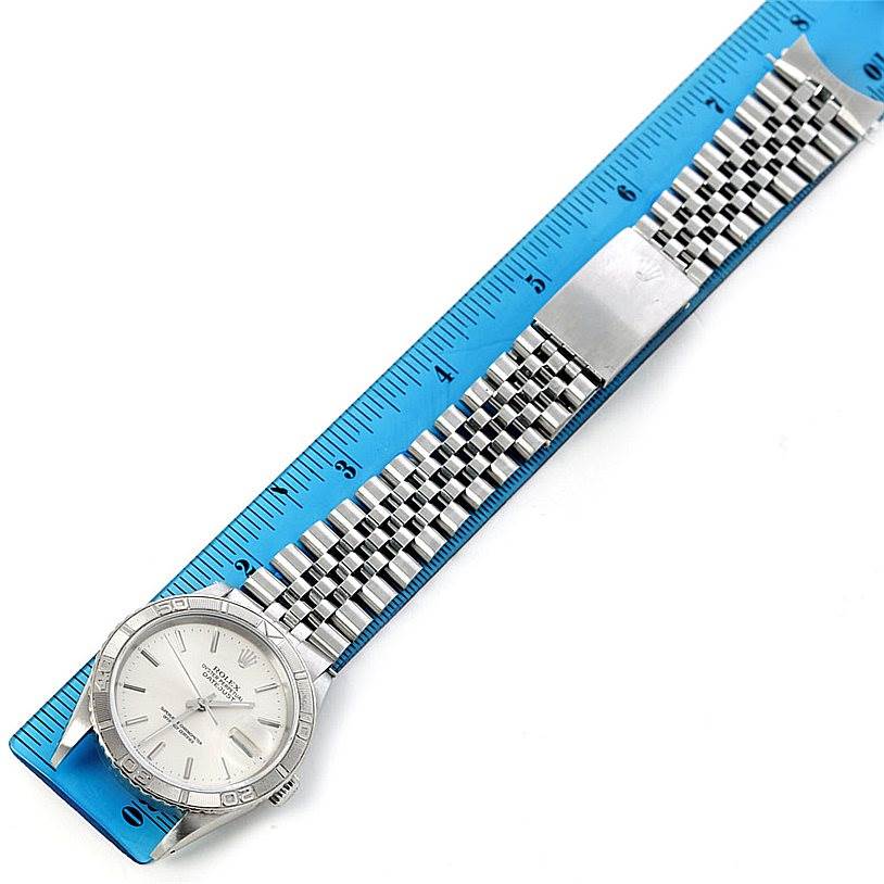 The Rolex Turn-o-Graph 16264 Men's Stainless Steel White Dial 16264 Men's Stainless Steel White Dial watch is shown from a side angle, displaying the face, bezel, bracelet, and clasp, with a ruler beneath for measurement.