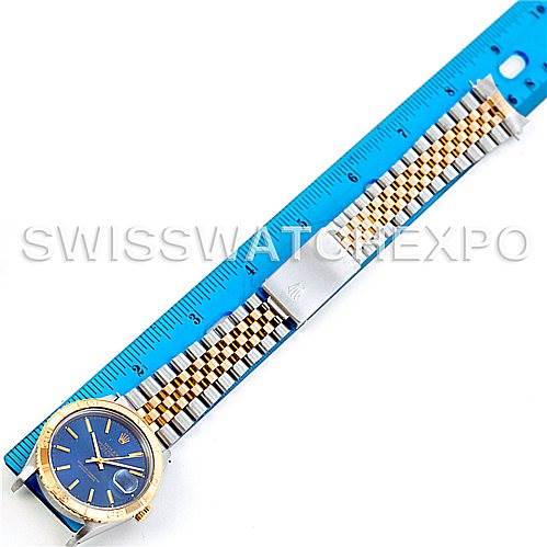 The Rolex Turn-o-Graph 16263 Men's Steel and Gold (two tone) Blue Dial 16263 Men's Steel and Gold (two tone) Blue Dial watch is shown from a top-down angle with its blue dial, bracelet, and partial view of a blue ruler.