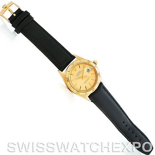 The image shows a top-down view of a Rolex Turn-o-Graph 1625 Men's Yellow Gold Champagne Dial 1625 Men's Yellow Gold Champagne Dial watch, displaying the gold casing, face, and black leather strap.