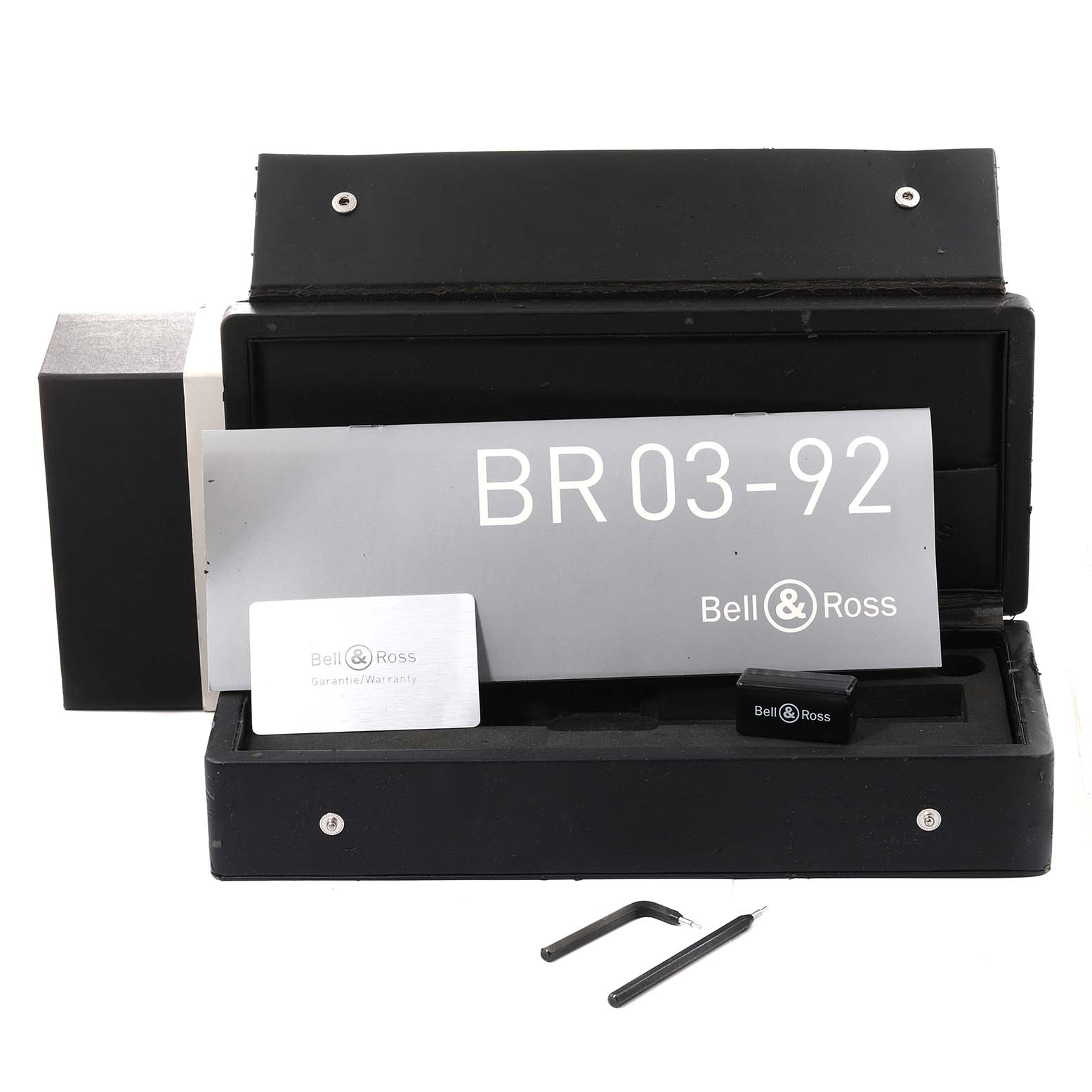 The image shows an open watch box for the Bell 
Ross Instruments BR03-92-S Men
s Stainless Steel Black Dial BR03-92-S Men
s Stainless Steel Black Dial BR03-92, displaying the manual, warranty card, and tools.