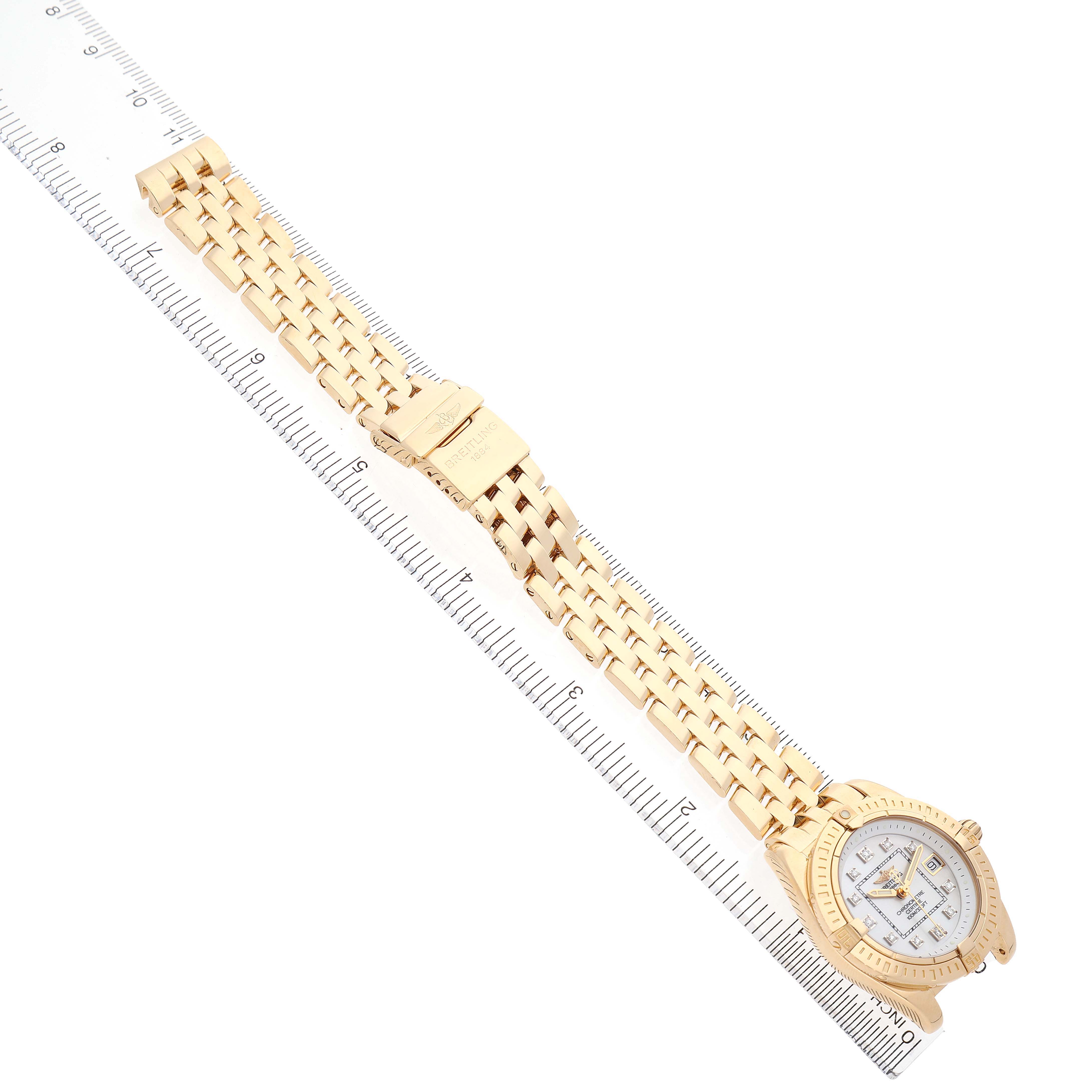 The Breitling K71356 Women's Yellow Gold Mother of Pearl Dial Cockpit Lady K71356 watch is shown from a top view, displaying its bracelet, clasp, and face with a ruler.