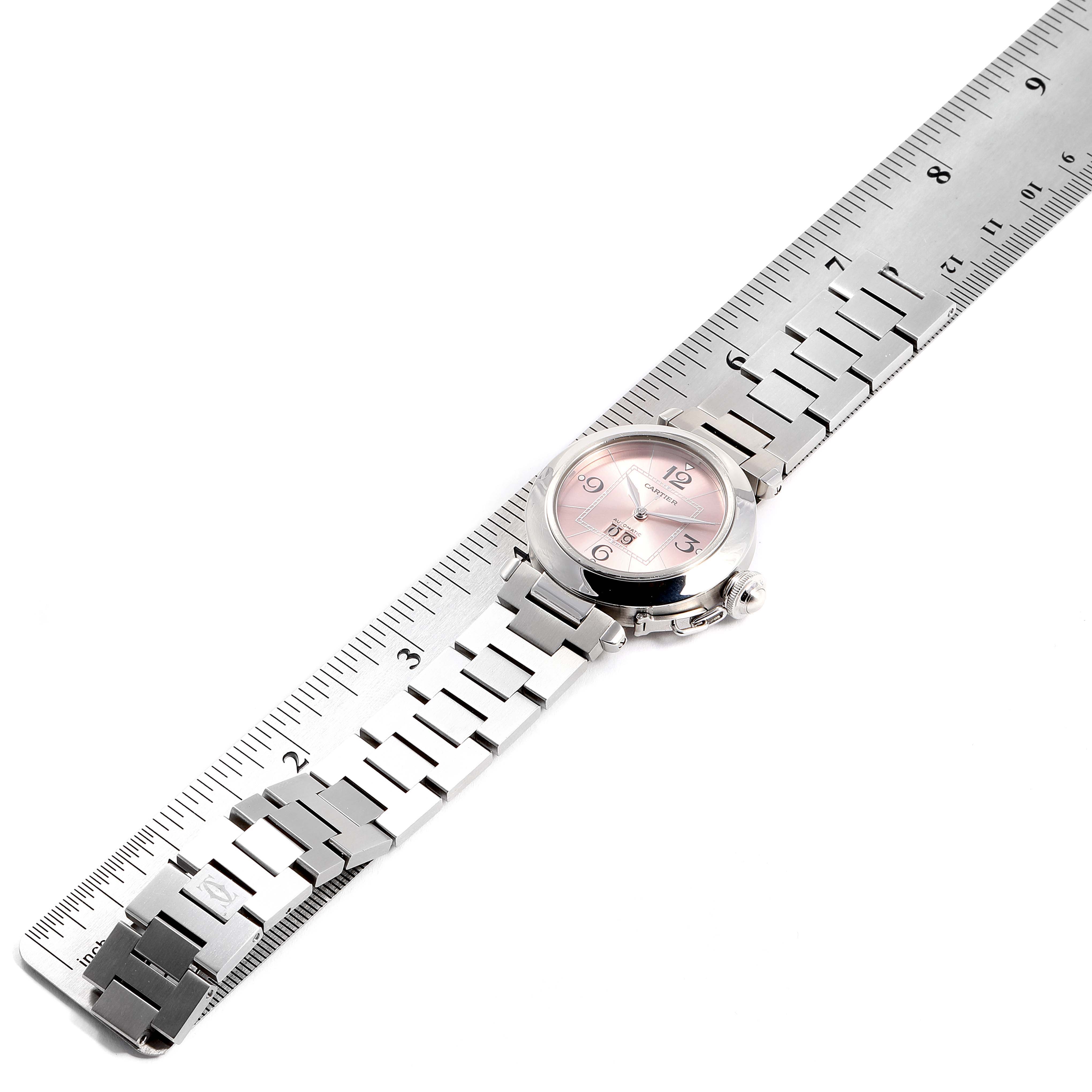 The Cartier Pasha W31058M7 Women
s Stainless Steel Pink Dial W31058M7 Women
s Stainless Steel Pink Dial watch is shown from an overhead angle, including its band and partly the face alongside a ruler.