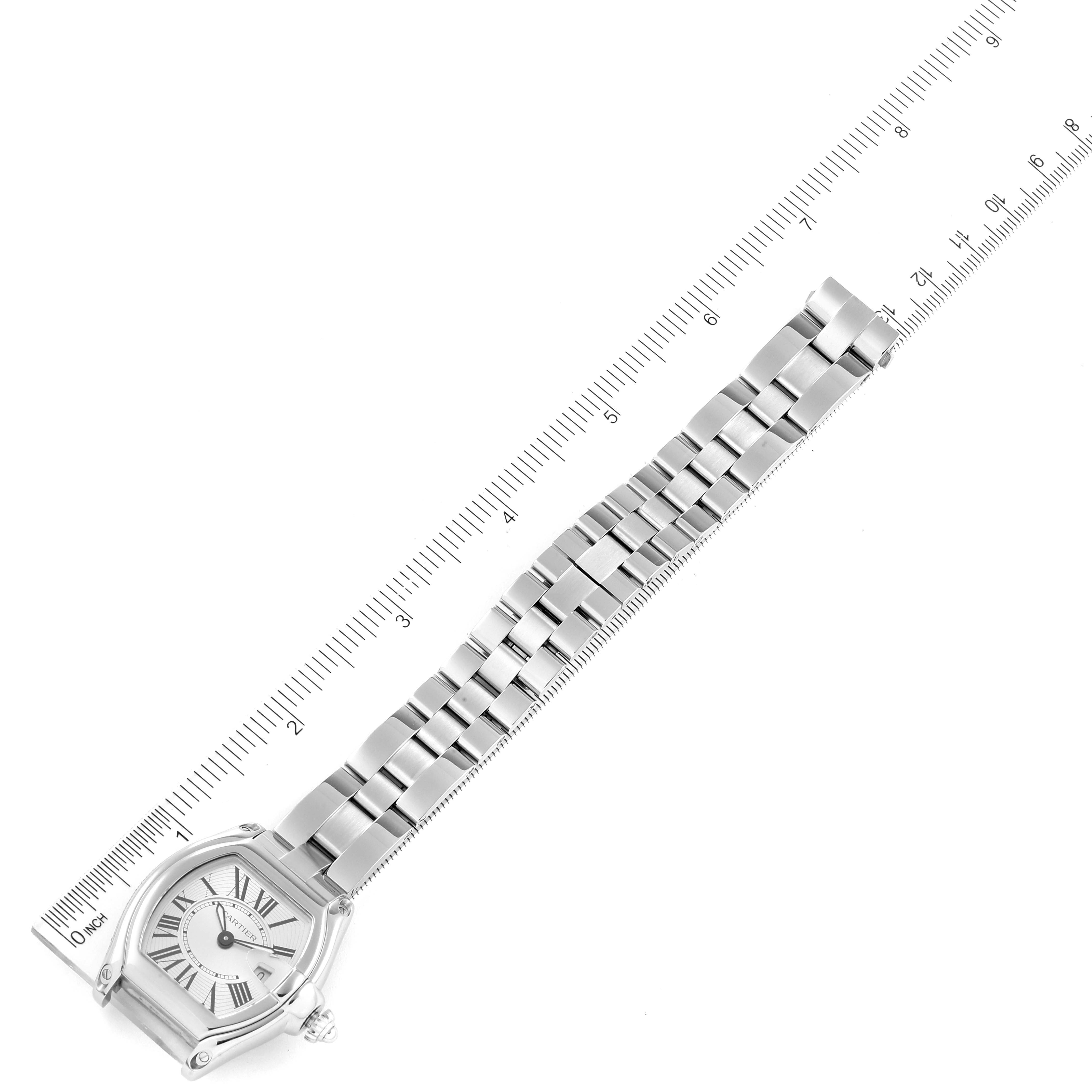 The image shows a top-down view of a Cartier Roadster W62016V3 Women's Stainless Steel Silver Dial W62016V3 Women's Stainless Steel Silver Dial watch with its full metal band next to a ruler for scale.