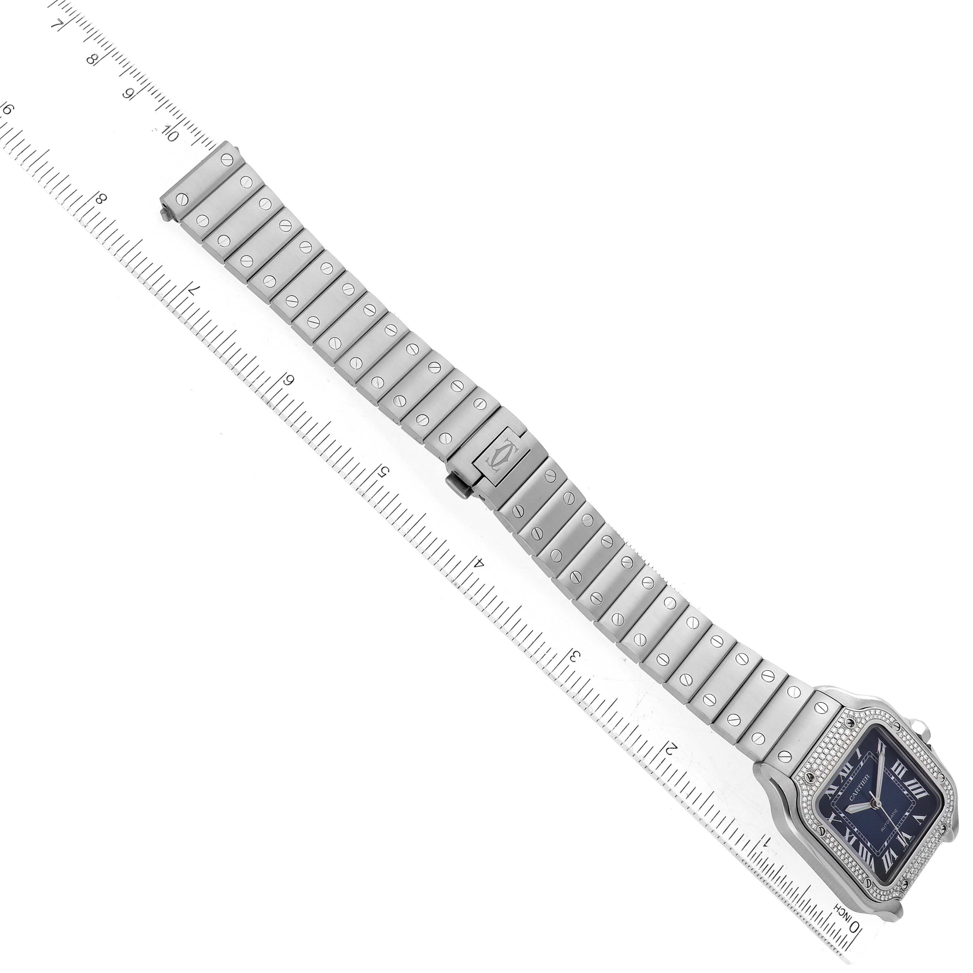 The image shows a Santos model watch by Cartier, displayed from an aerial view with the watch band extended and a ruler beside it.