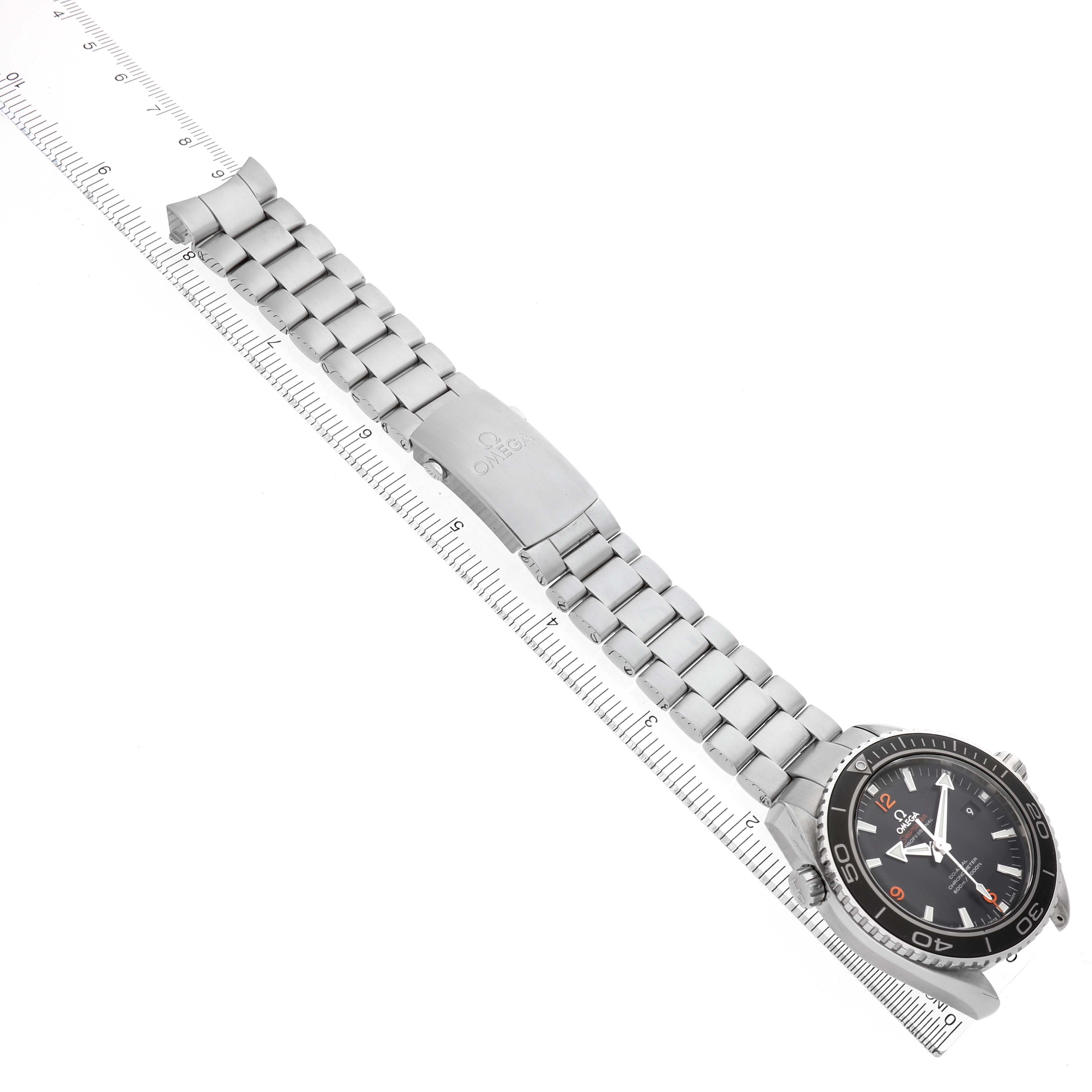 The Omega Planet Ocean 232.30.46.21.01.003 Men's Stainless Steel Black Dial watch is shown at an angled top view, displaying the face, bezel, bracelet, and clasp alongside a ruler.