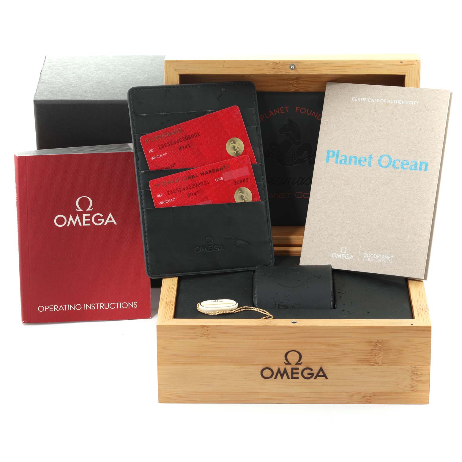 The image shows the packaging and accessories for the Omega Planet Ocean 232.32.44.22.03.001 Men's Stainless Steel Blue Dial 232.32.44.22.03.001 Men's Stainless Steel Blue Dial watch, including a wooden box, booklets, and cards.