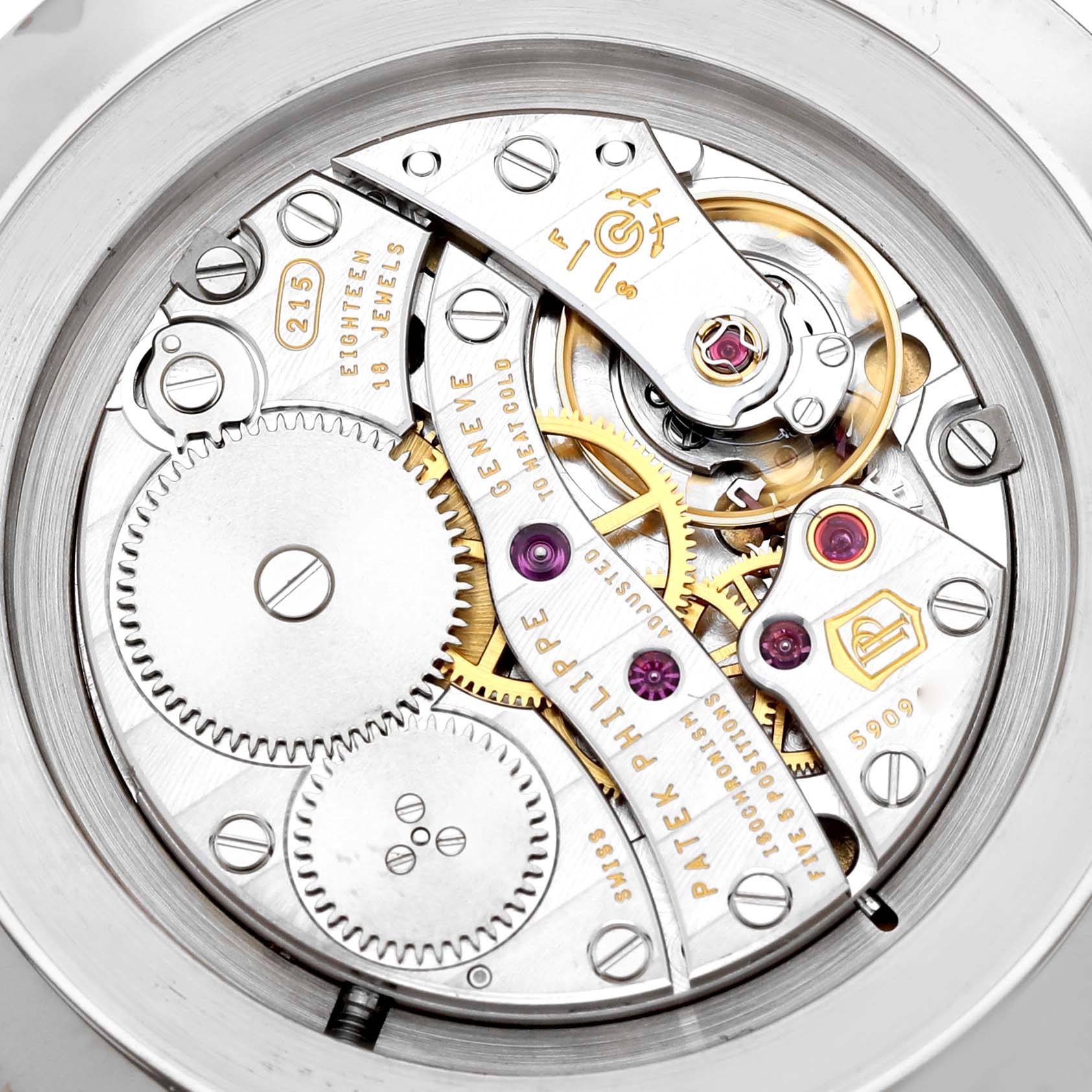 The image shows a close-up of the intricate movement mechanism of the Patek Philippe Calatrava 5119G-001 Men's White Gold White Dial watch, highlighting gears and jewels.