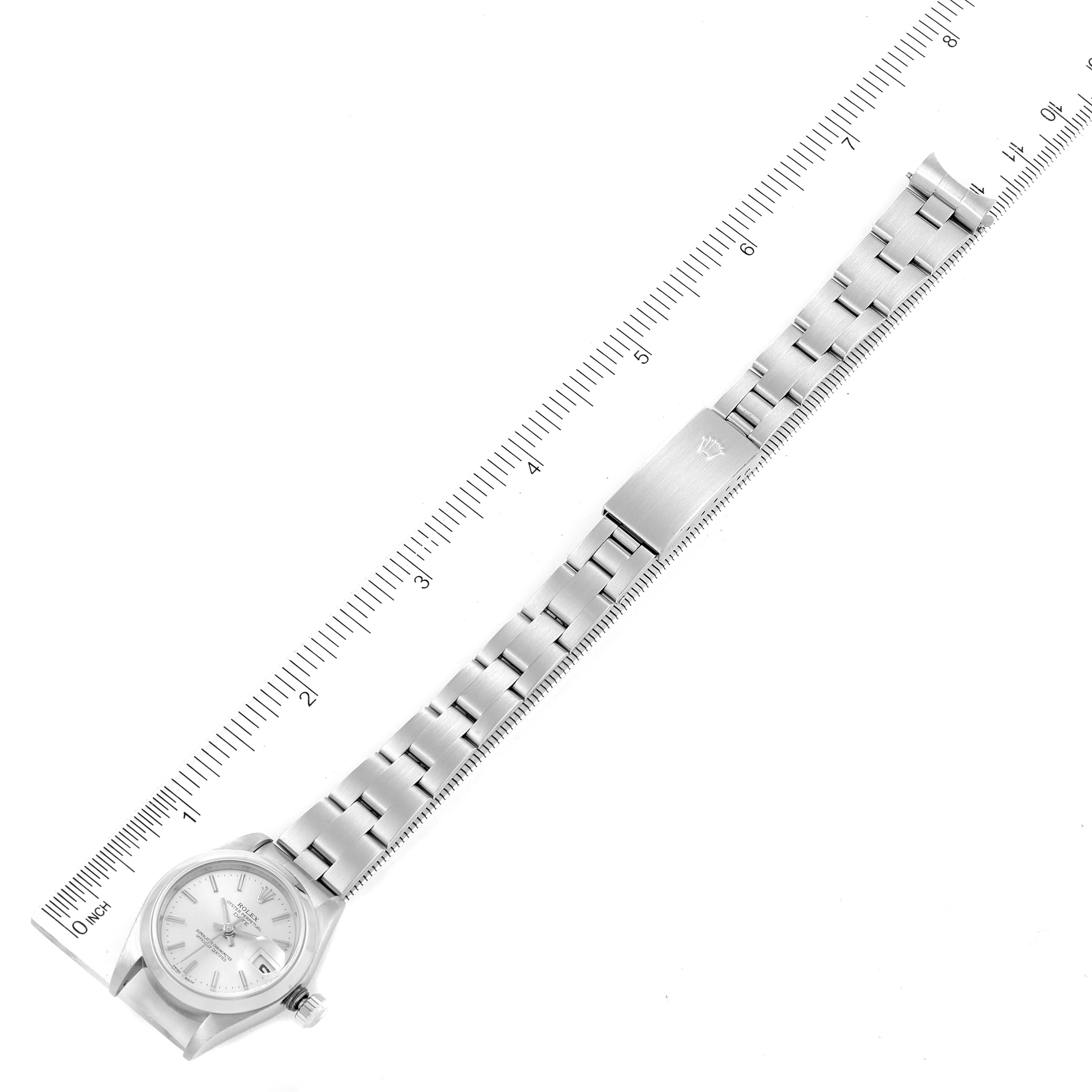 The image shows a top-down view of a Rolex Date 79160 Women's Stainless Steel Silver Dial 79160 Women's Stainless Steel Silver Dial watch, featuring the face, bracelet, and clasp alongside a ruler for scale.