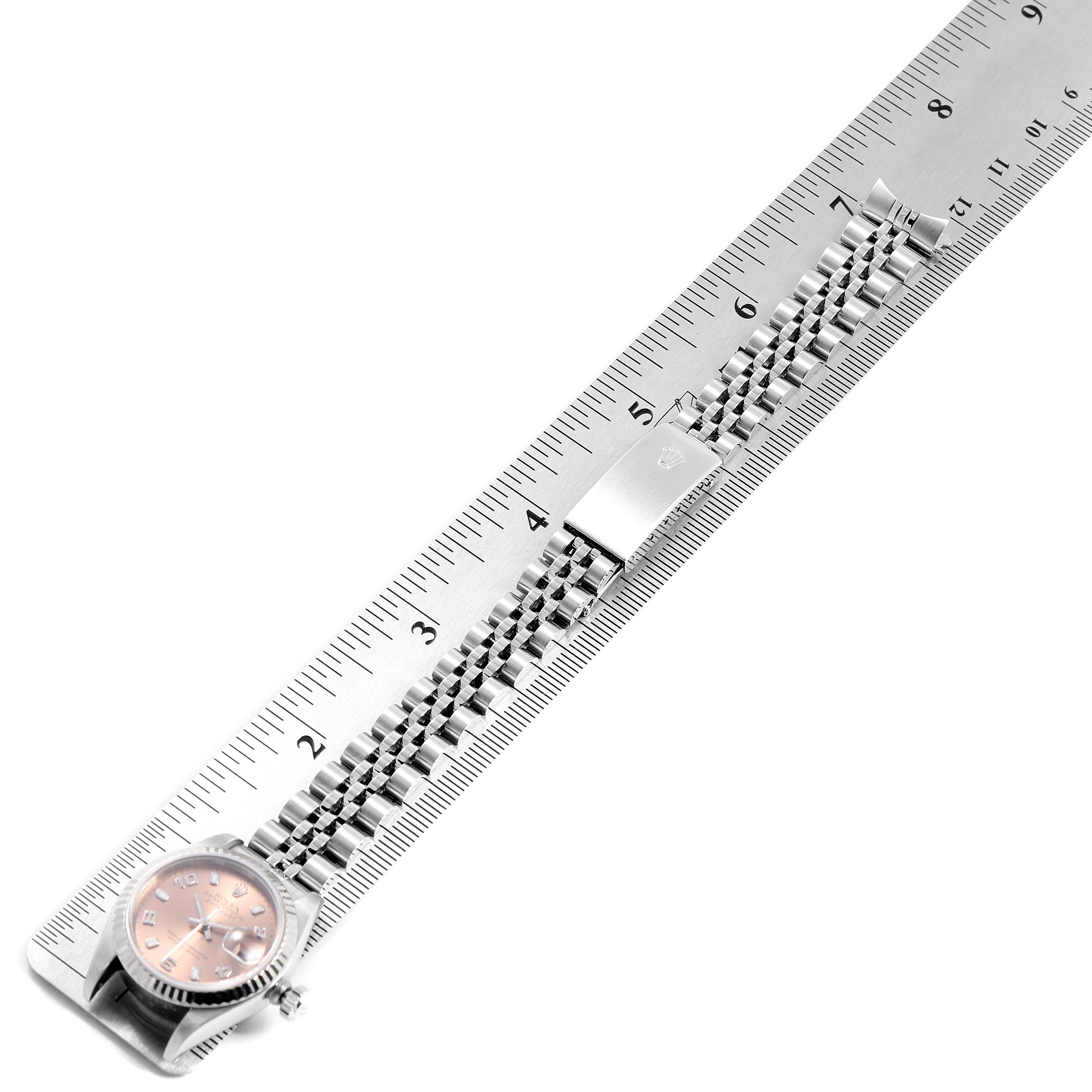 The image shows a Rolex Datejust 79174 Women
s Stainless Steel Pink Dial 79174 Women
s Stainless Steel Pink Dial watch with its bracelet laid out alongside a ruler for measurement.