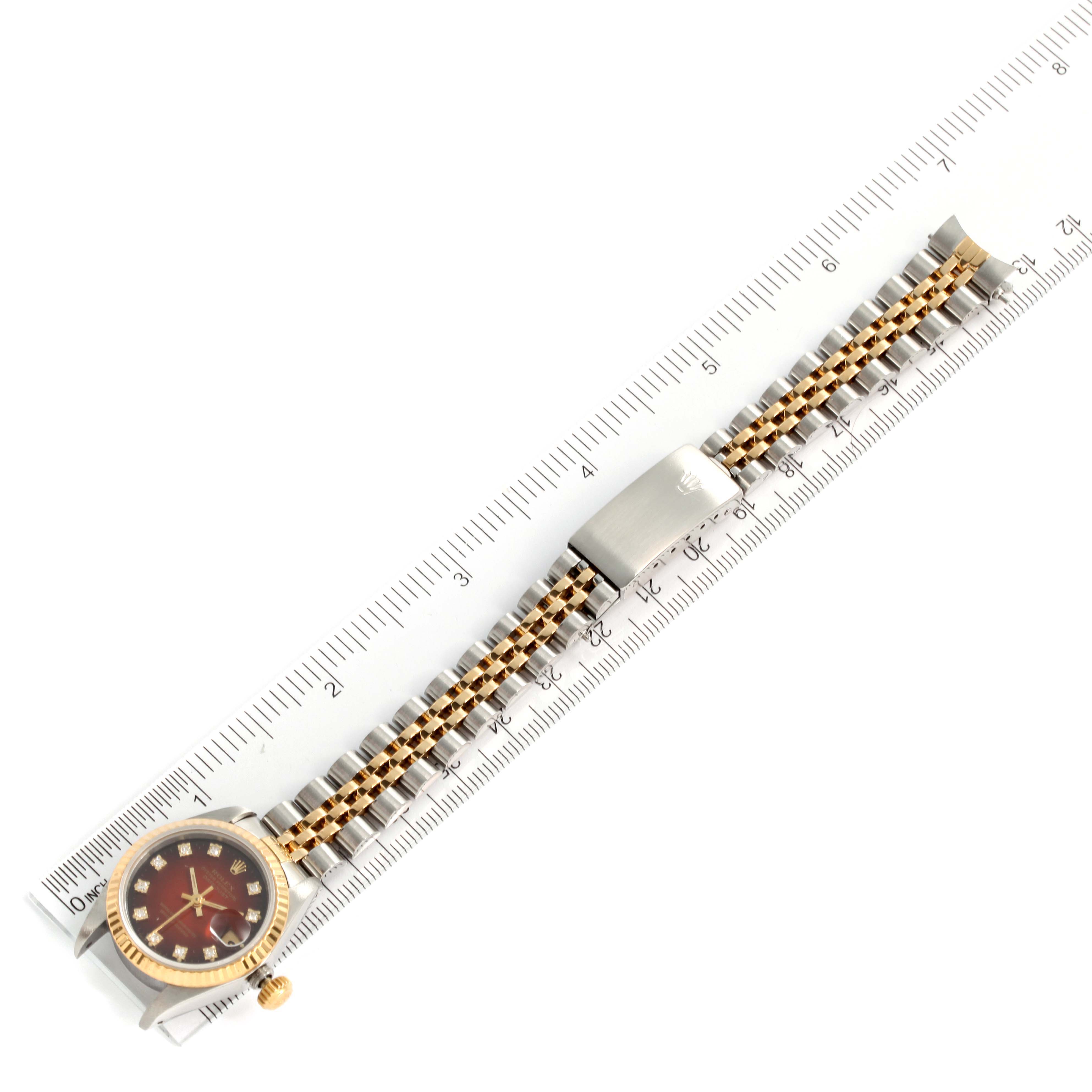 The image shows the Rolex Datejust 69173 Women's Steel and Gold (two tone) Red Dial 69173 Women's Steel and Gold (two tone) Red Dial model watch lying flat against a ruler, showcasing the dial, crown, and bracelet.