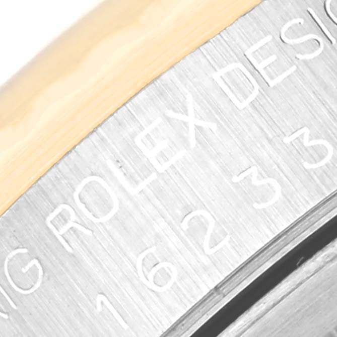 This is a close-up of the side of the case of a Rolex Datejust 16233 Men's Steel and Gold (two tone) Black Dial 16233 Men's Steel and Gold (two tone) Black Dial, showing the engraved writing "ROLEX DESIGN" and part of the model number.