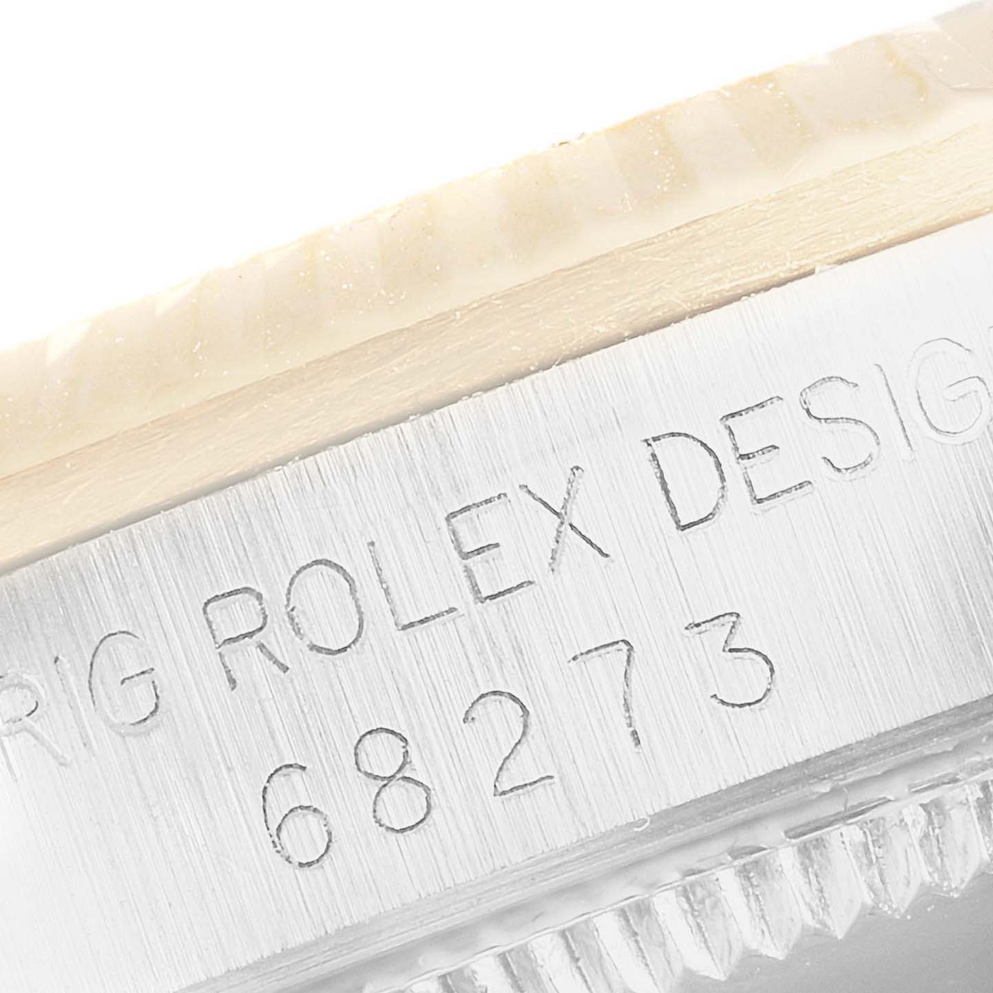 The image shows a close-up of a Rolex Mid-Size 68273 Women
s Steel and Gold (two tone) White Dial 68273 Women
s Steel and Gold (two tone) White Dial model
s serial number and part of the bezel and case.