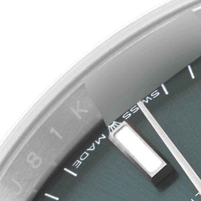 The image shows a close-up angle of the dial, bezel, and markers of a Rolex Datejust 126200 Men's Stainless Steel Green Dial 126200 Men's Stainless Steel Green Dial watch.
