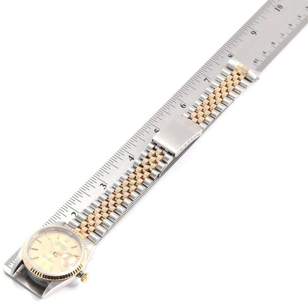 The Rolex Datejust 16233 Men
s Steel and Gold (two tone) Champagne Dial 16233 Men
s Steel and Gold (two tone) Champagne Dial watch is shown laid flat with a ruler for scale, displaying the face, bezel, crown, and bracelet.