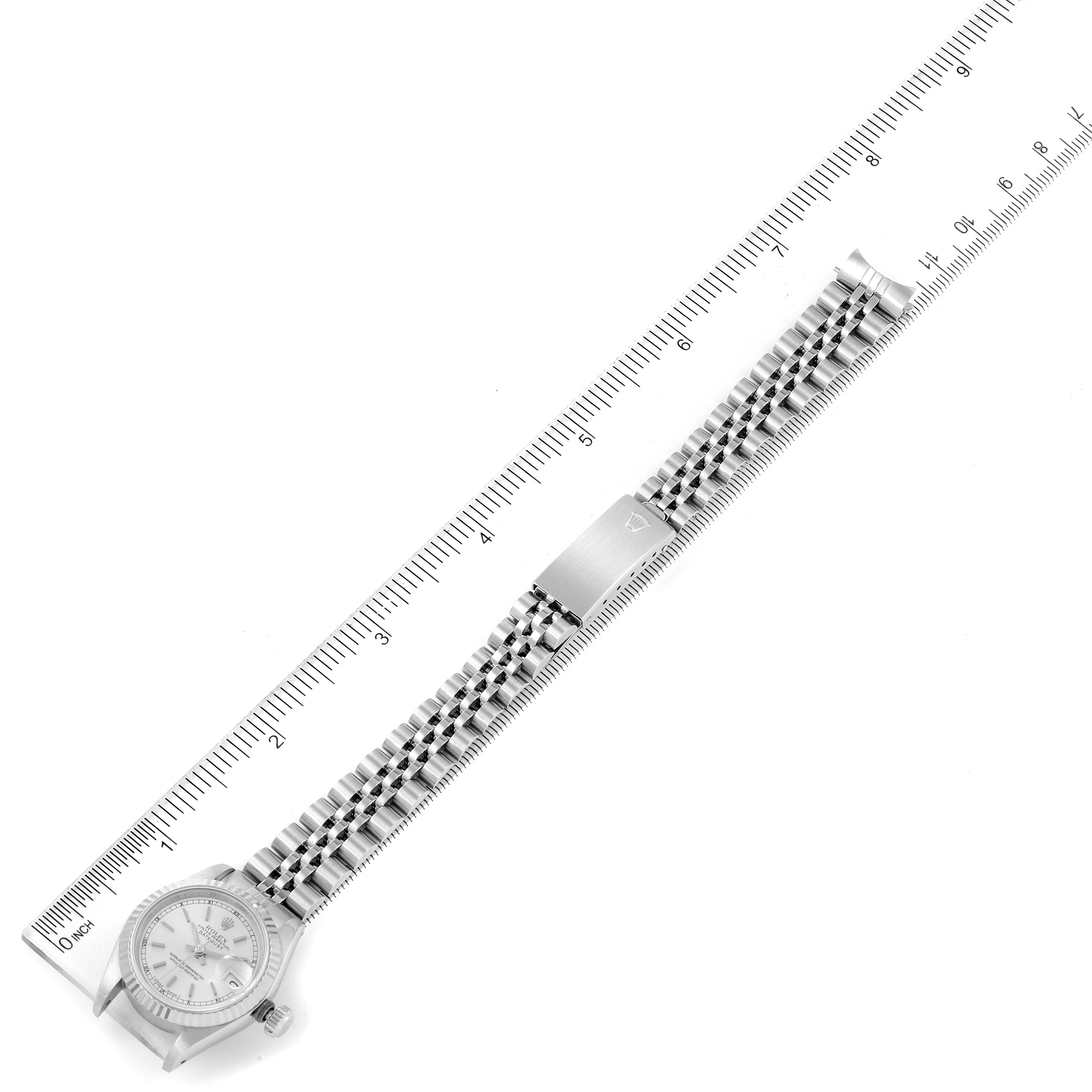 The image shows a top-down view of a Rolex Datejust 69174 Women
s Stainless Steel Silver Dial 69174 Women
s Stainless Steel Silver Dial watch with its band fully extended alongside a ruler.