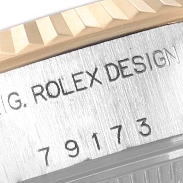 This image shows a close-up angle of the Rolex Datejust 79173 Women's Steel and Gold (two tone) Blue Dial 79173 Women's Steel and Gold (two tone) Blue Dial model's fluted bezel and case, featuring the engraving "G. ROLEX DESIGN."