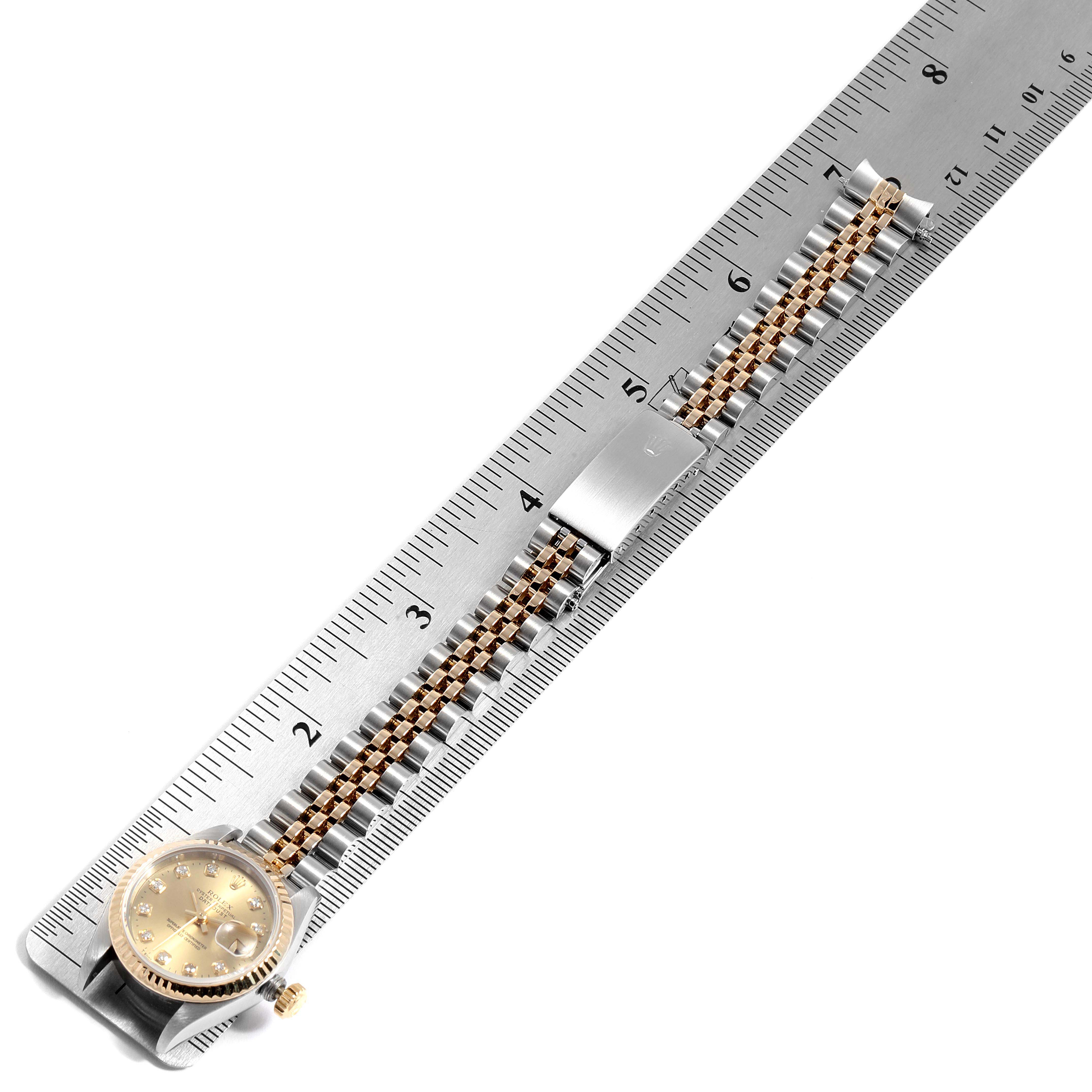 The image shows the Rolex Datejust 69173 Women
s Steel and Gold (two tone) Champagne Dial 69173 Women
s Steel and Gold (two tone) Champagne Dial watch lying flat with its bracelet stretched along a ruler.