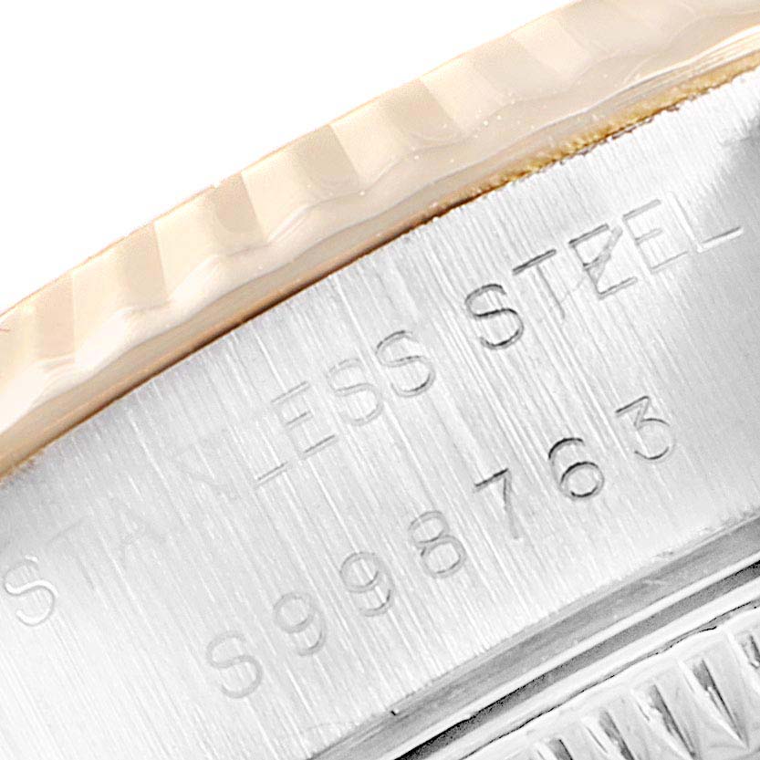 The image shows a close-up of the side of a Rolex Datejust 69173 Women
s Steel and Gold (two tone) Champagne Dial 69173 Women
s Steel and Gold (two tone) Champagne Dial watch, featuring its fluted bezel and serial number engraving.