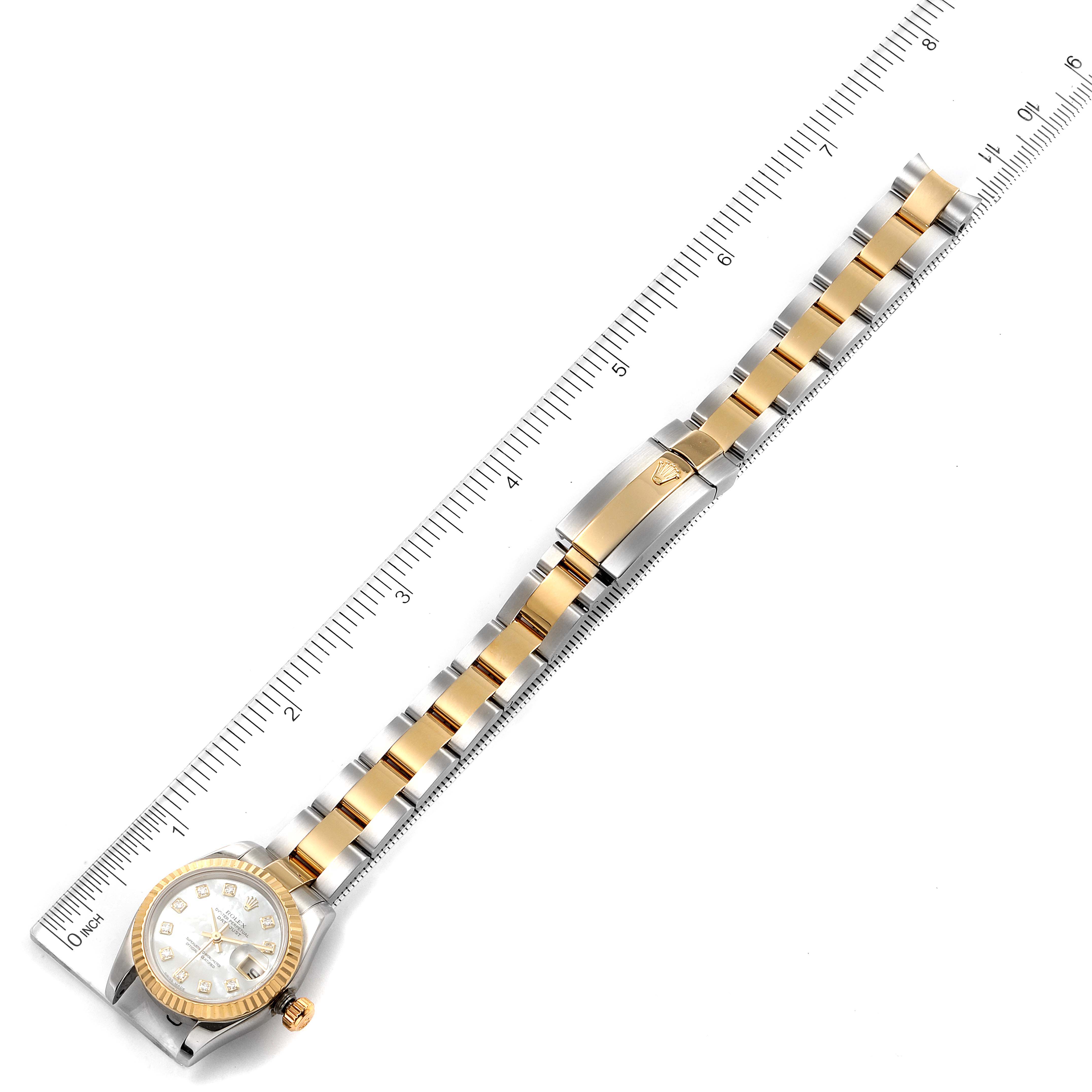 This image shows a top view of a Rolex Datejust 179173 Women's Steel and Gold (two tone) Mother of Pearl Dial 179173 Women's Steel and Gold (two tone) Mother of Pearl Dial watch, displaying the face, bracelet, and clasp, aligned next to a ruler.